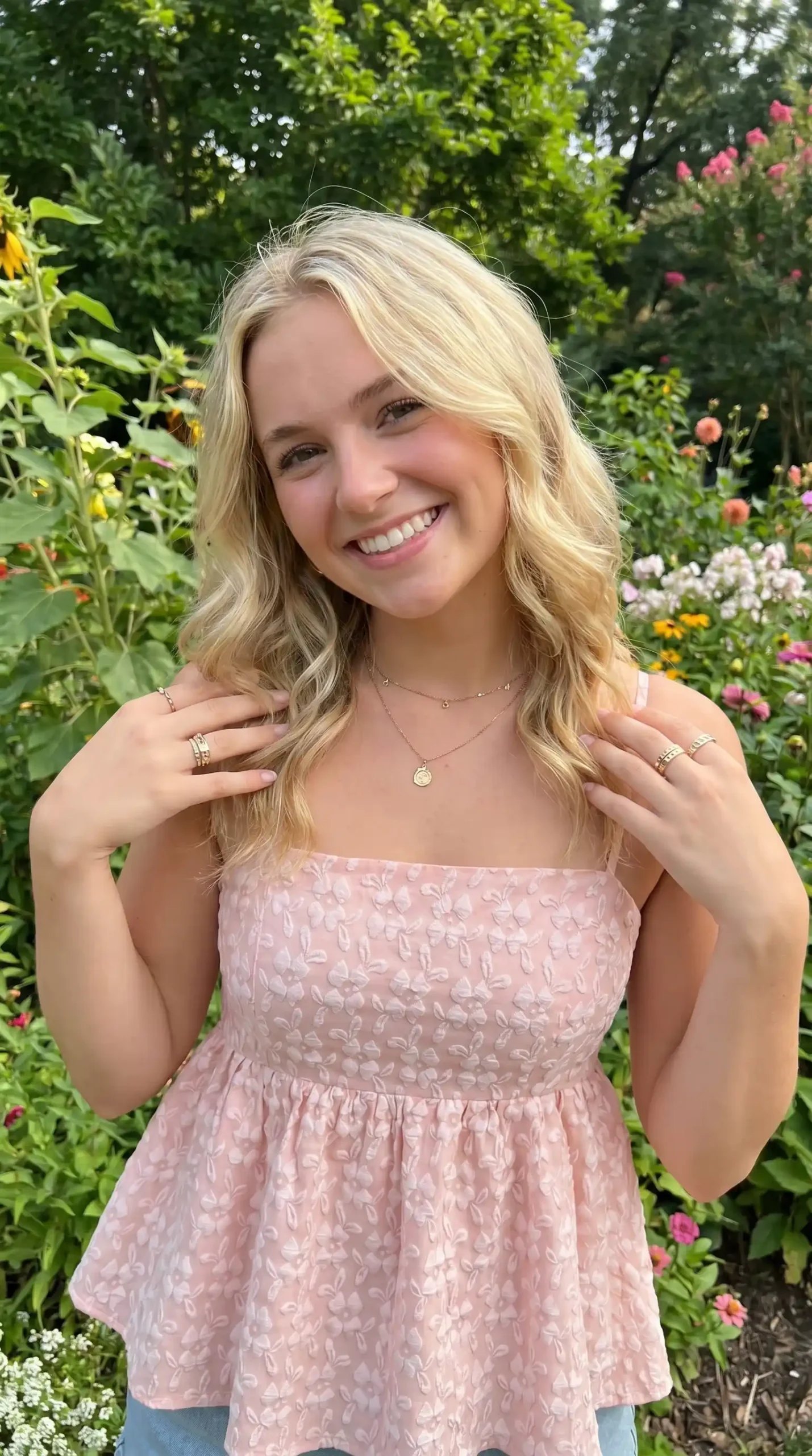 Woman wearing blush pink floral textured spaghetti strap babydoll top in a garden