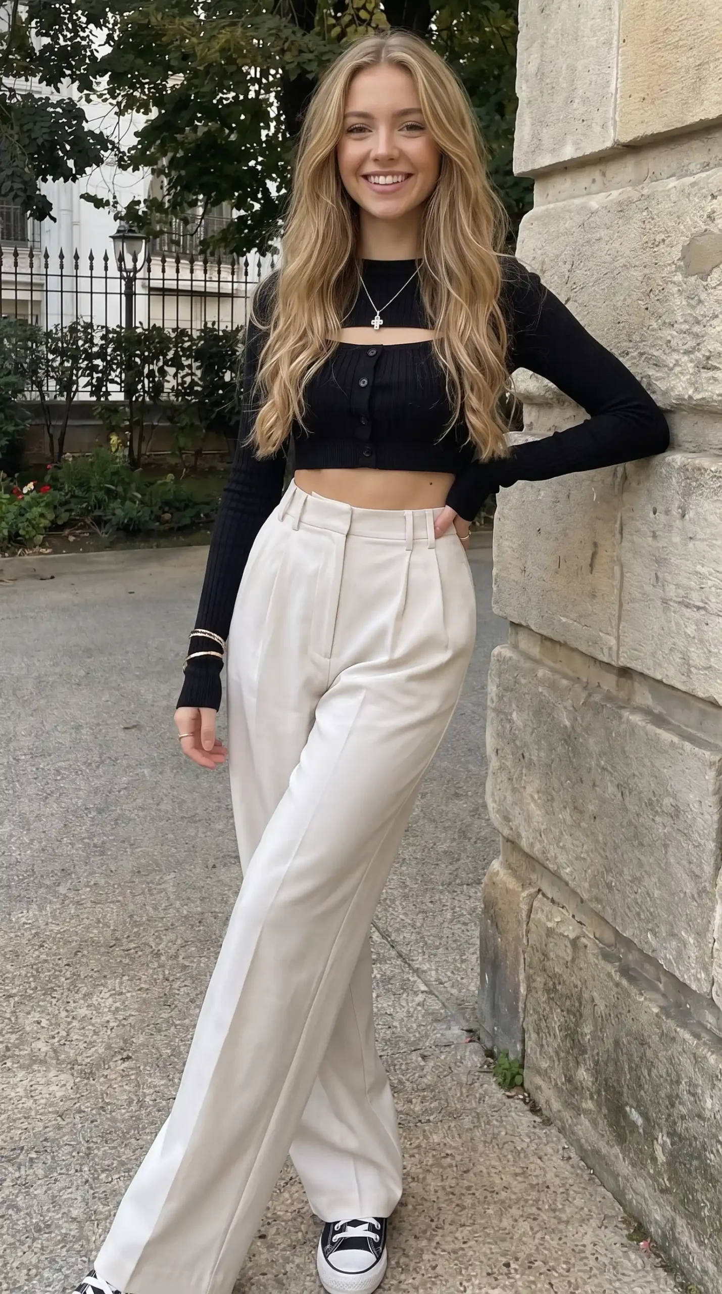 Woman wearing black ribbed button-front long sleeve crop top with cream wide-leg trousers and black Converse sneakers