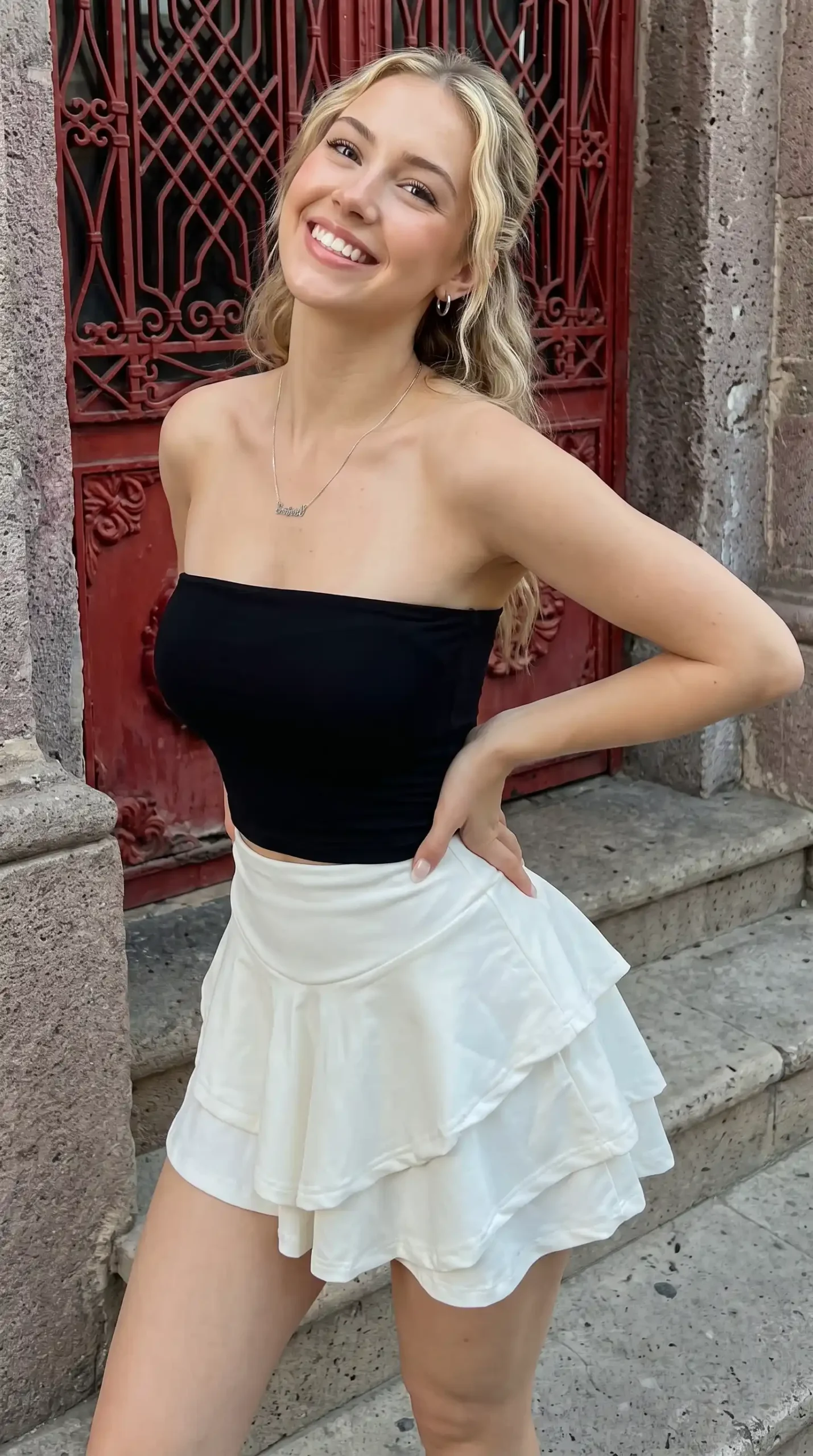 Woman wearing black tube crop top with white tiered ruffle mini skirt outdoors