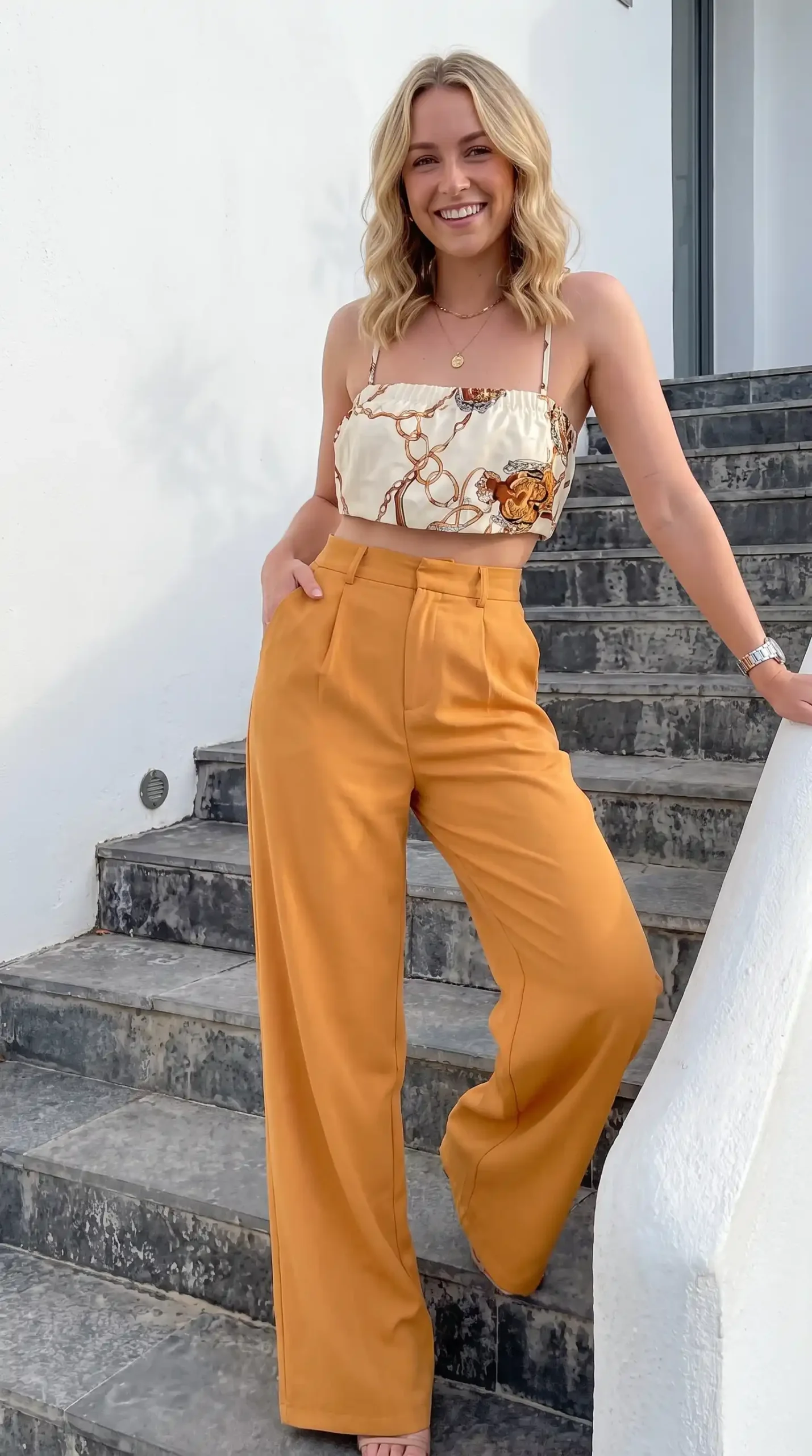 Woman wearing cream scarf print satin crop top with mustard yellow wide-leg trousers outdoors