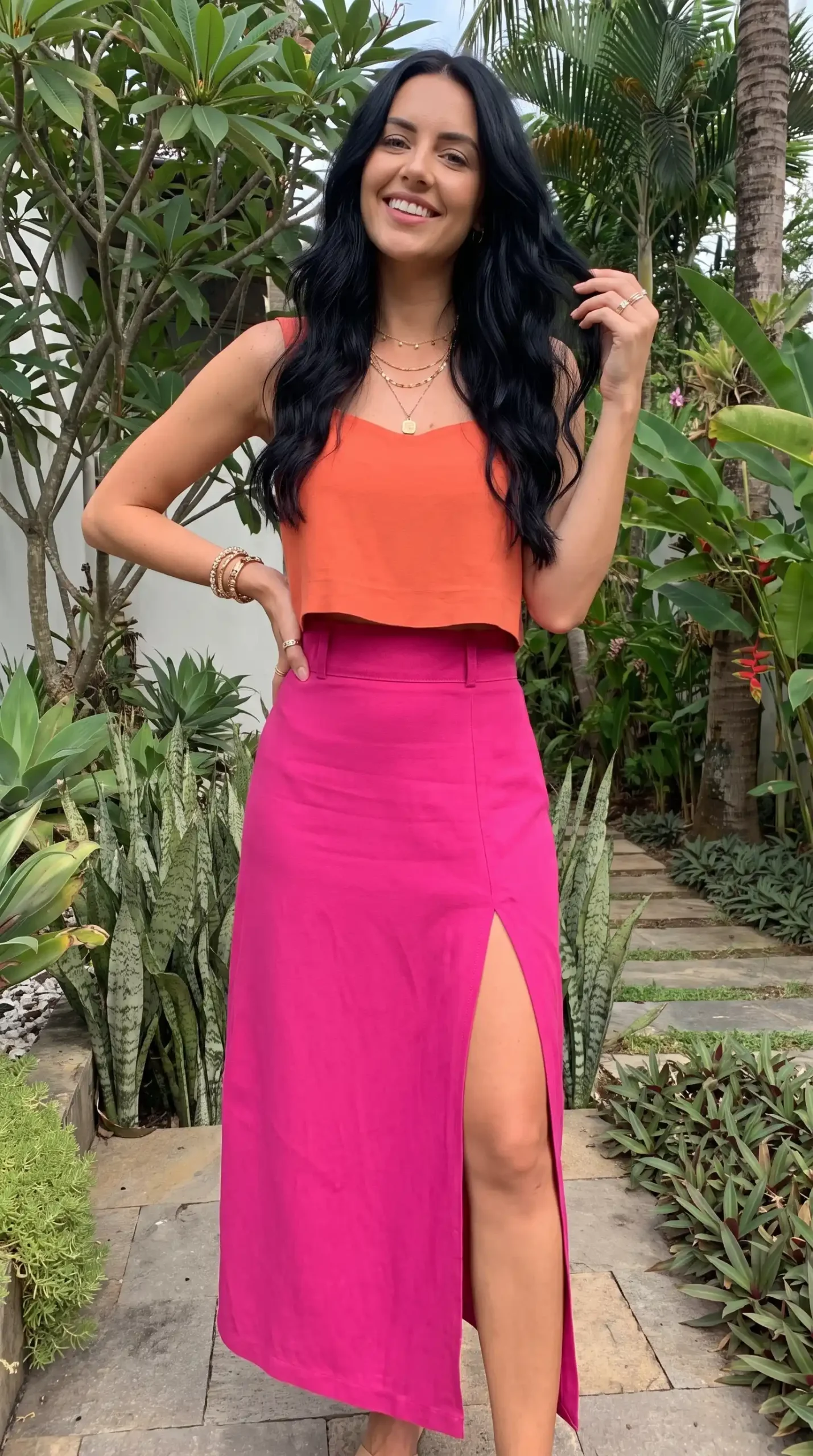 Woman wearing orange sweetheart neck crop top with hot pink high-waist slit midi skirt outdoors