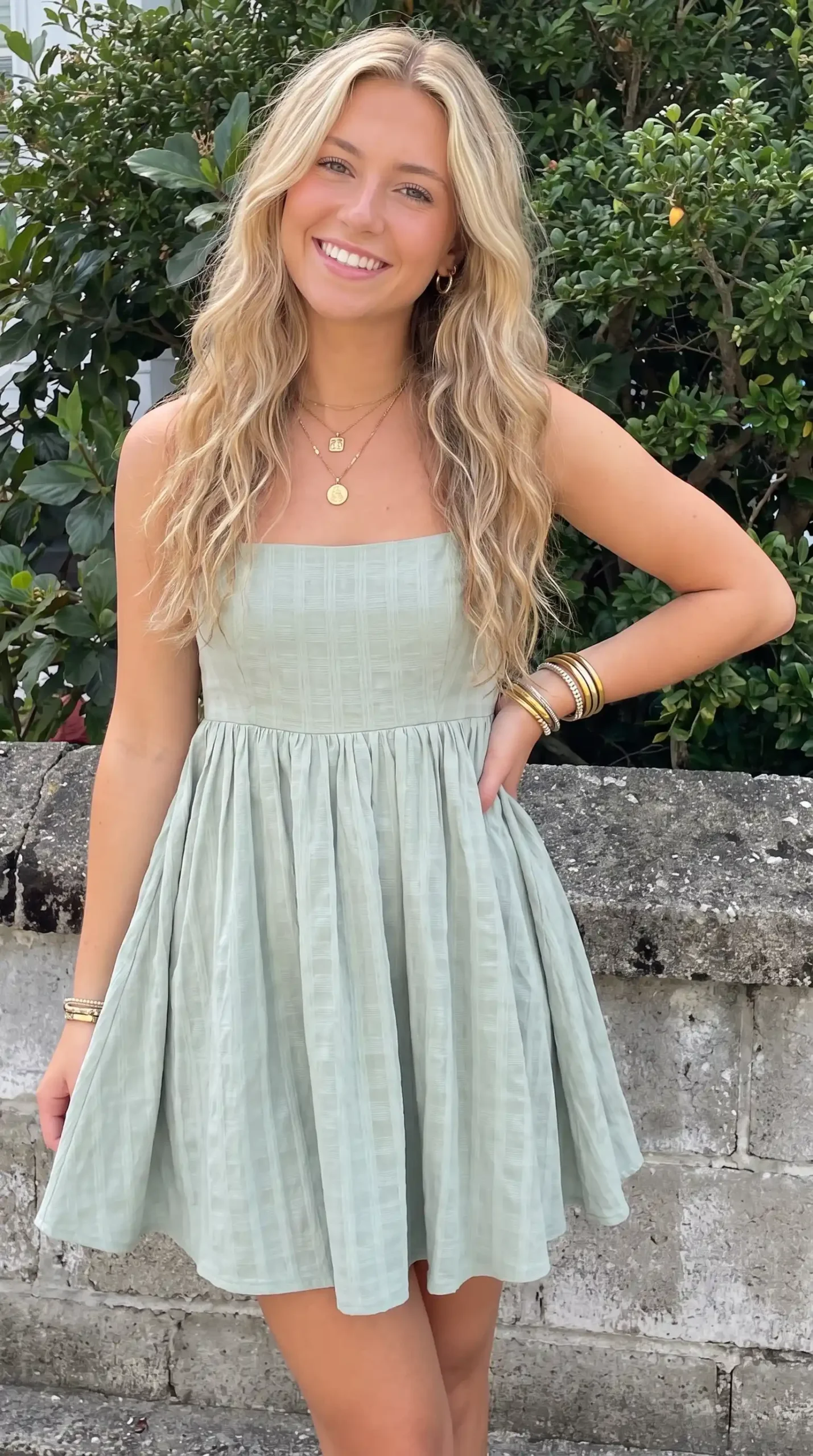 Woman wearing sage green textured strapless babydoll mini dress outdoors