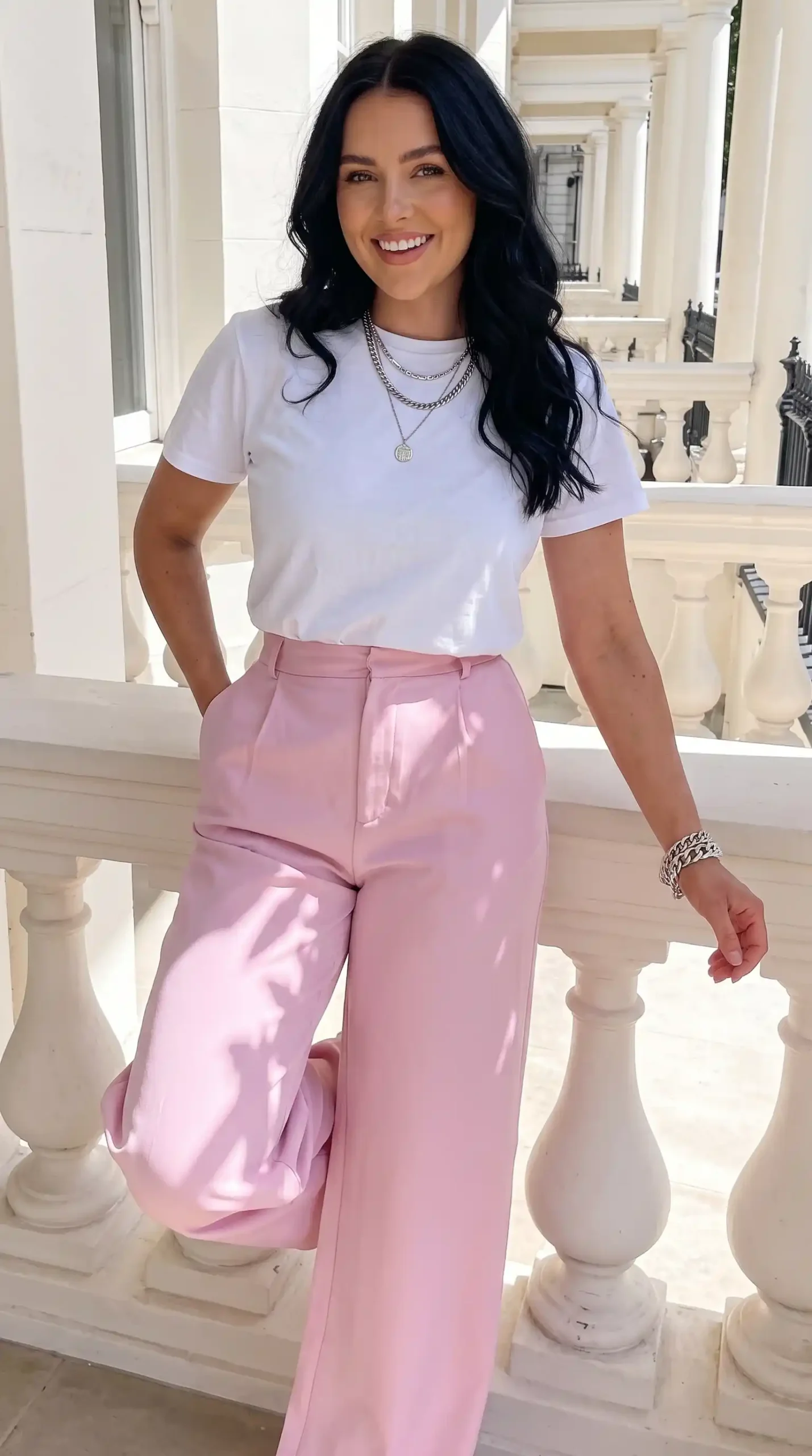 Woman wearing white crew neck t-shirt with blush pink satin wide-leg trousers outdoors