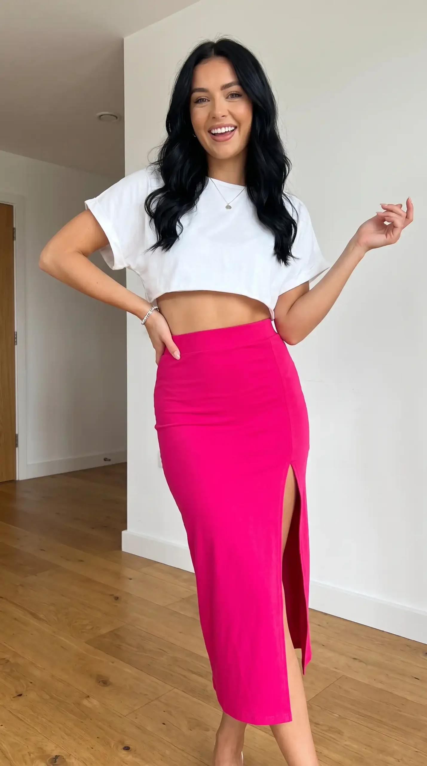 Woman wearing white oversized crop t-shirt with hot pink bodycon slit midi skirt indoors