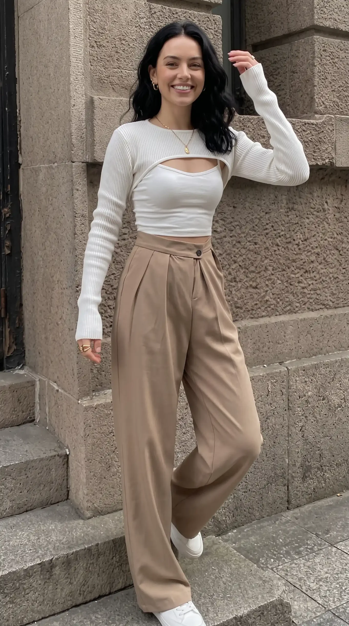Woman wearing white ribbed cut-out long sleeve crop top with taupe wide-leg trousers and white sneakers outdoors