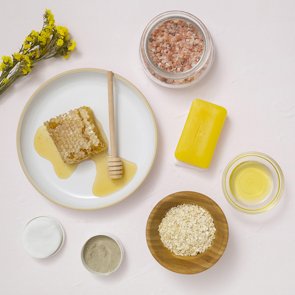 overhead-view-yellow-flower-cotton-pads-oats-essential-oil-soap-himalayan-rock-salt-white-textured-background.jpg