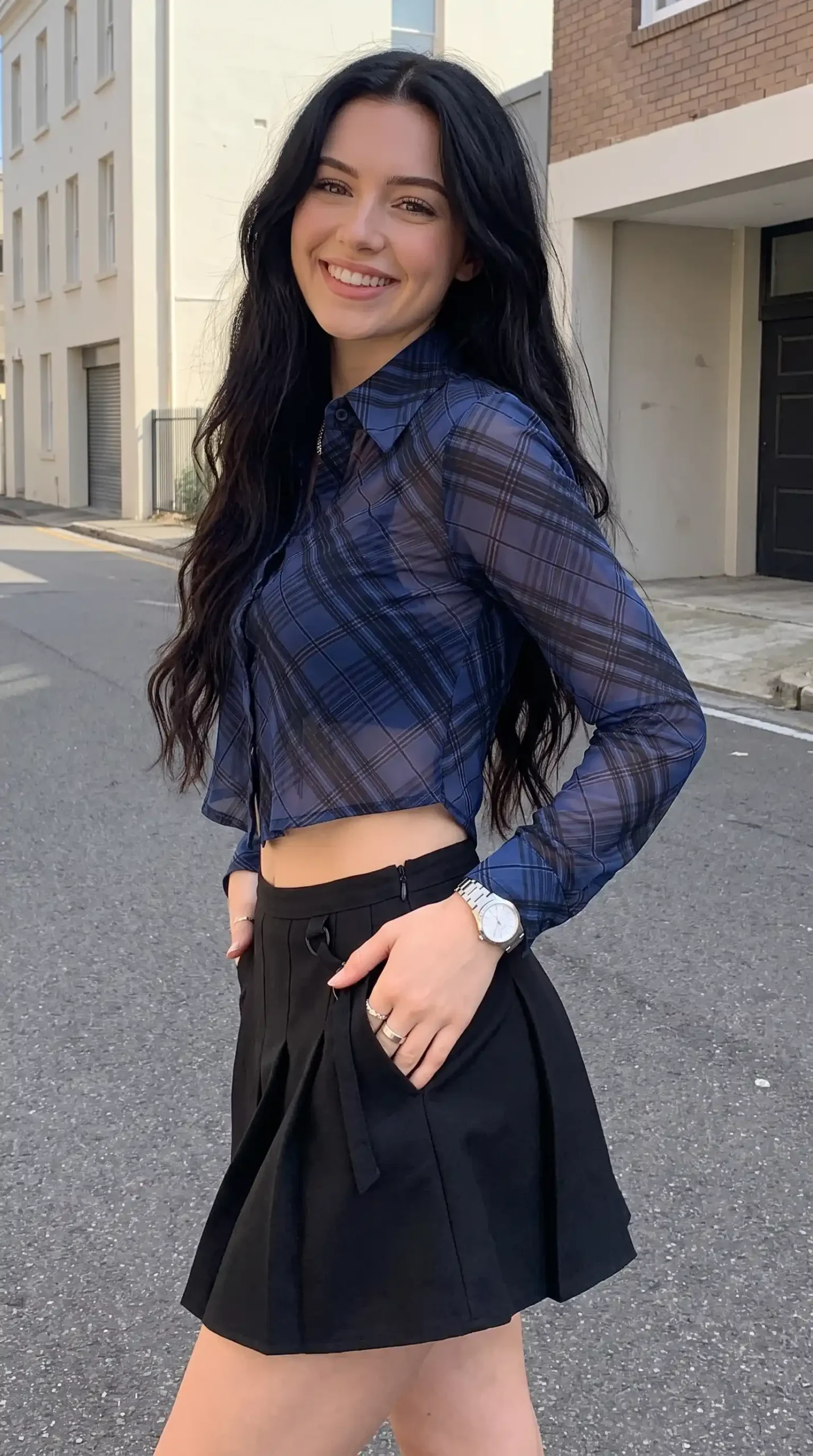 Woman wearing navy plaid sheer crop shirt with black pleated mini skirt outdoors