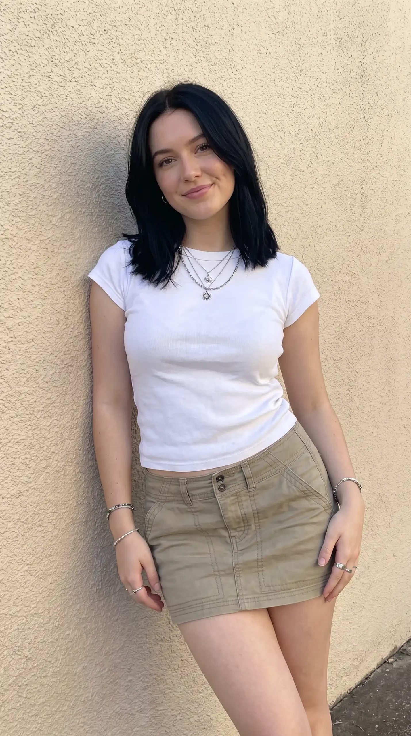 Woman wearing white fitted crop tee with khaki cargo mini skirt outdoors
