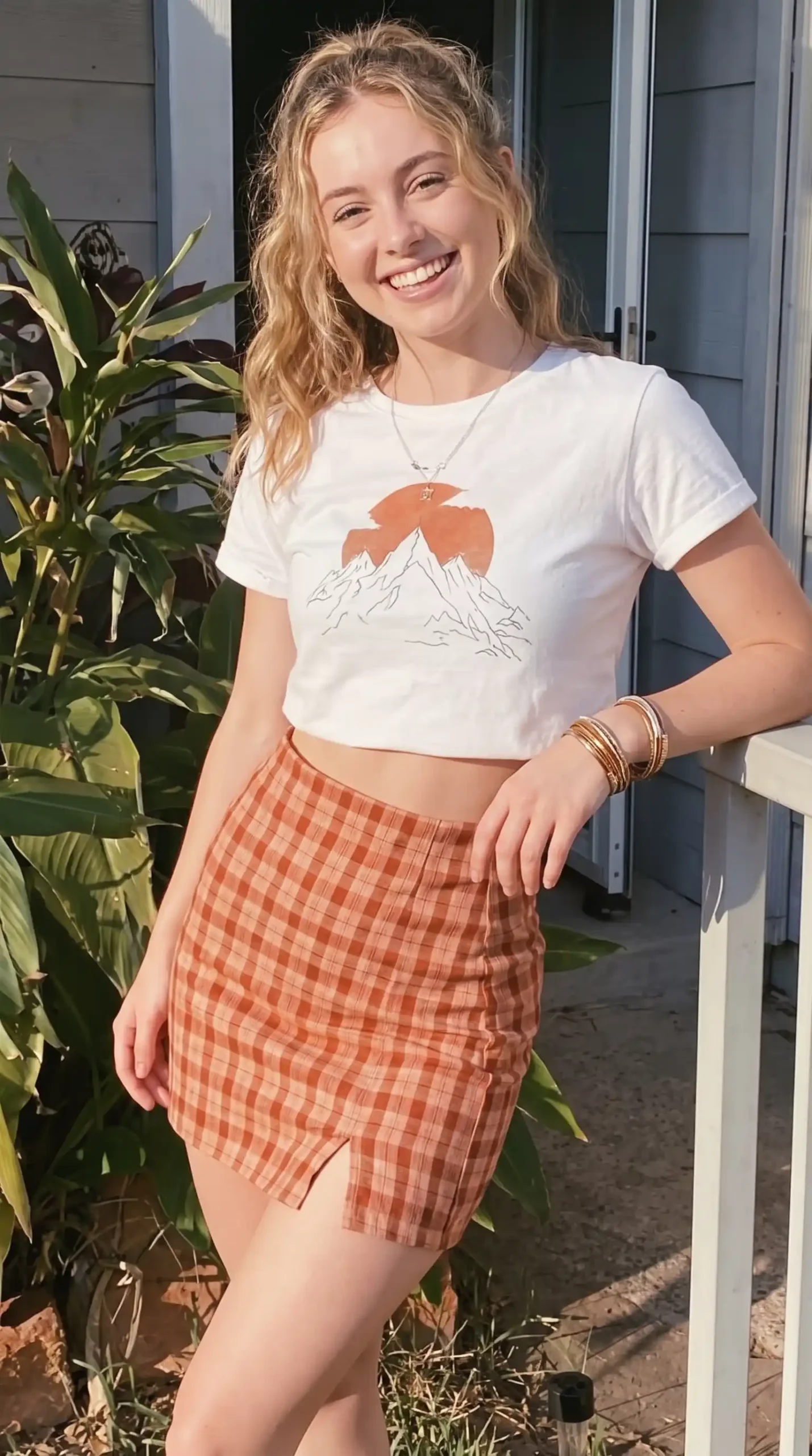 Woman wearing white graphic crop tee with rust orange plaid mini skirt outdoors
