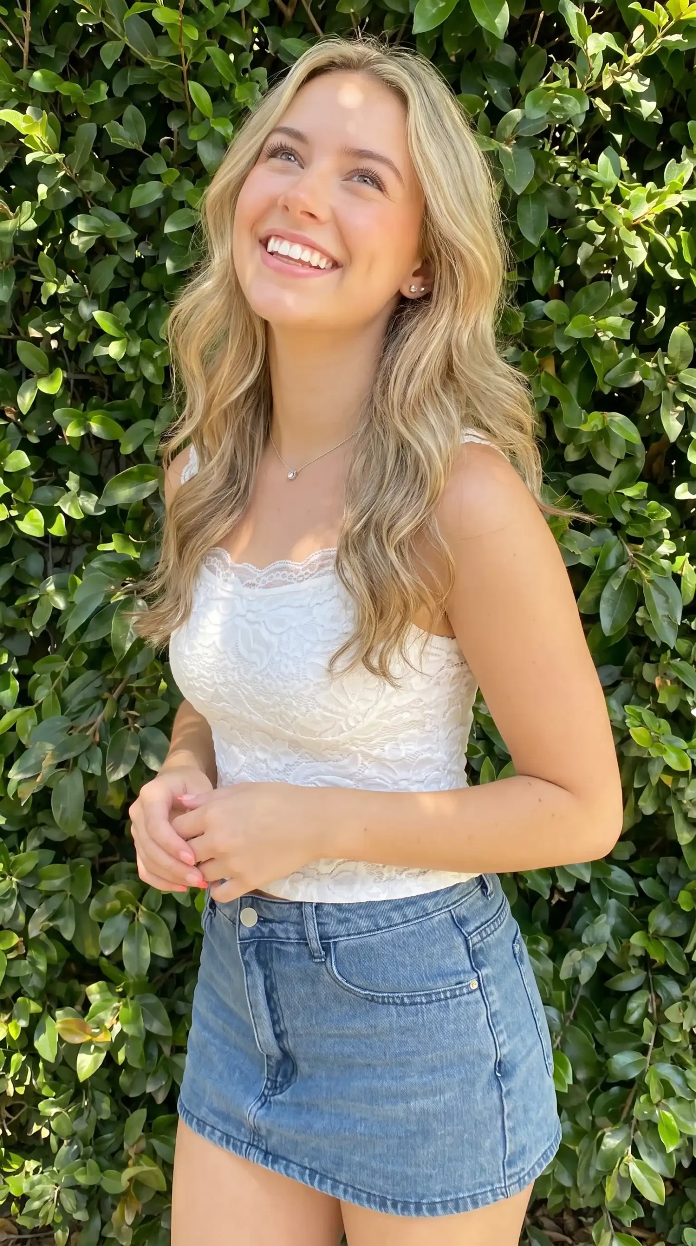 Woman wearing white lace cami with light wash denim mini skirt outdoors