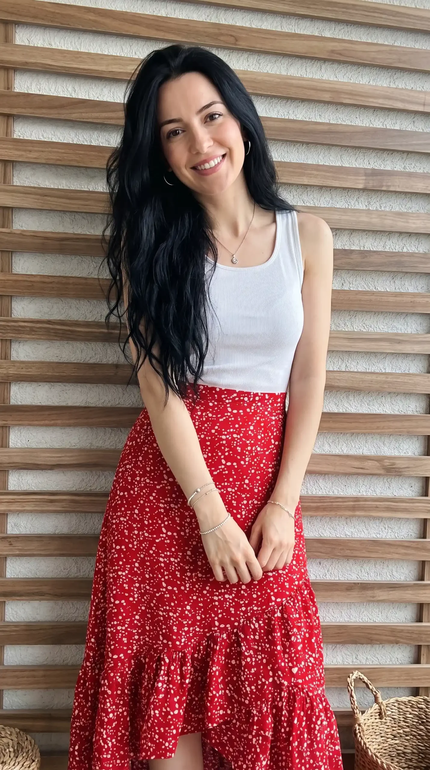 Woman wearing white ribbed tank top with red polka dot tiered maxi skirt indoors