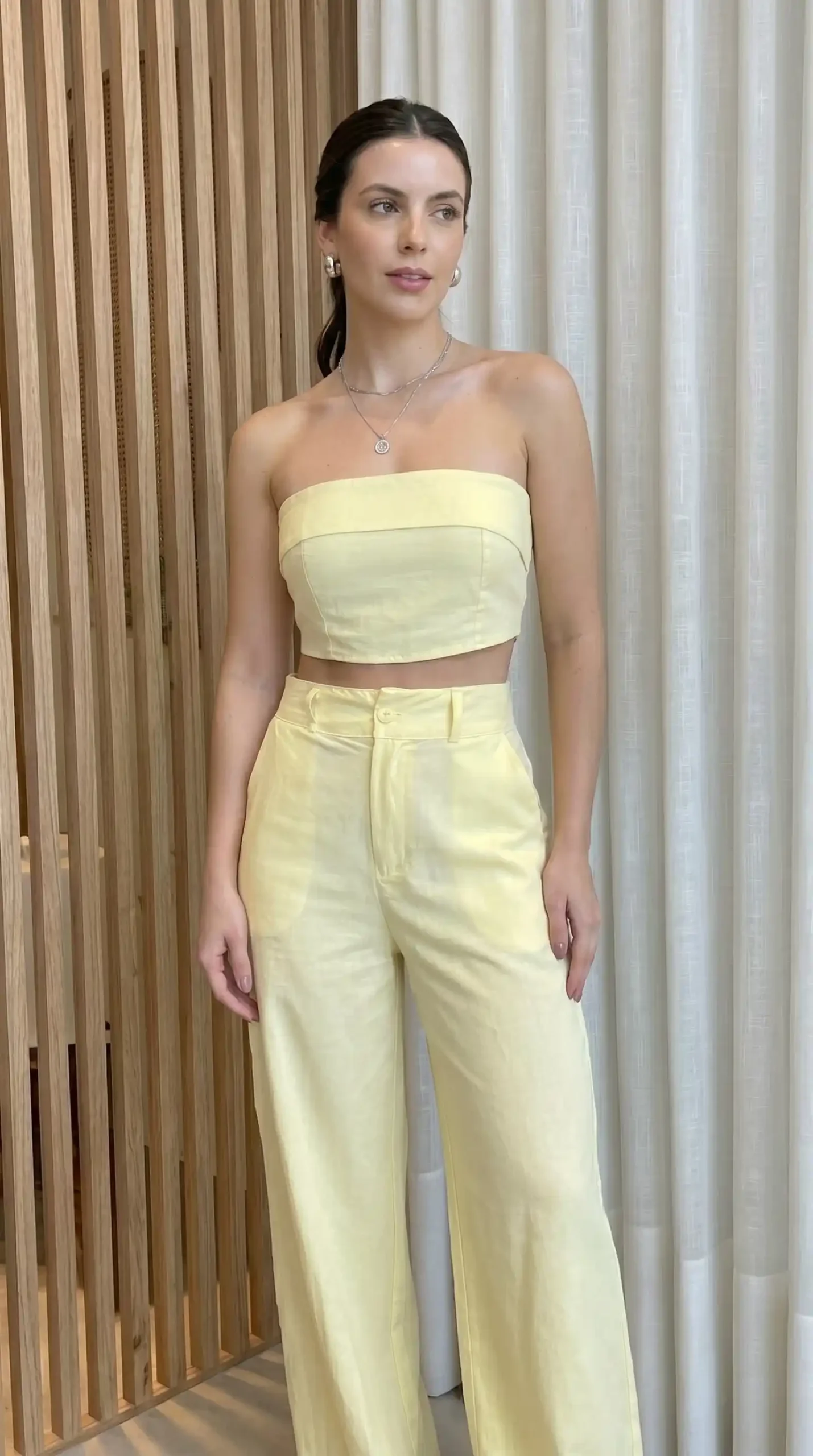 Woman wearing pale yellow tube top with matching wide-leg pants indoors