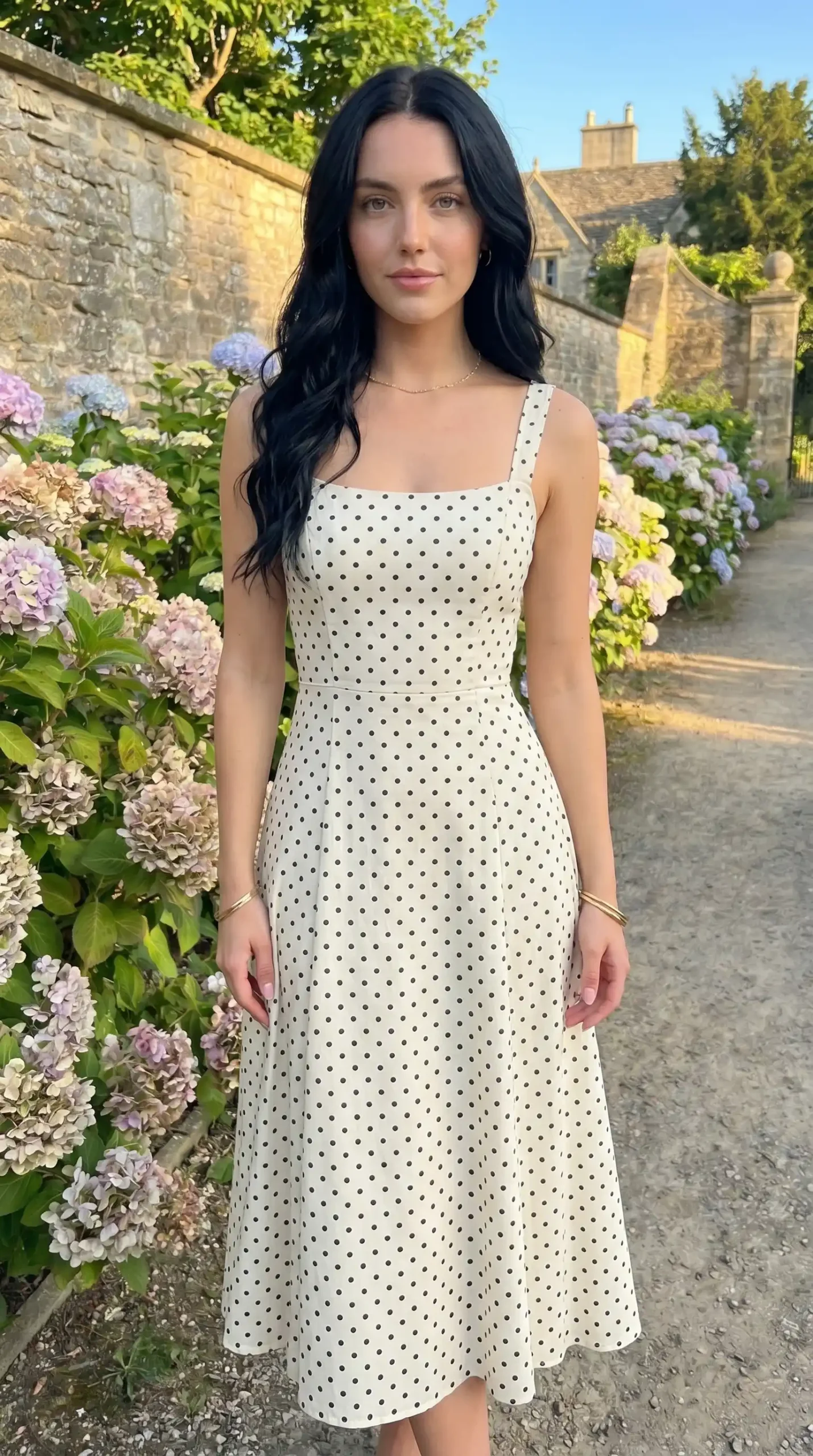 man wearing white and black polka dot midi dress in garden at golden hour