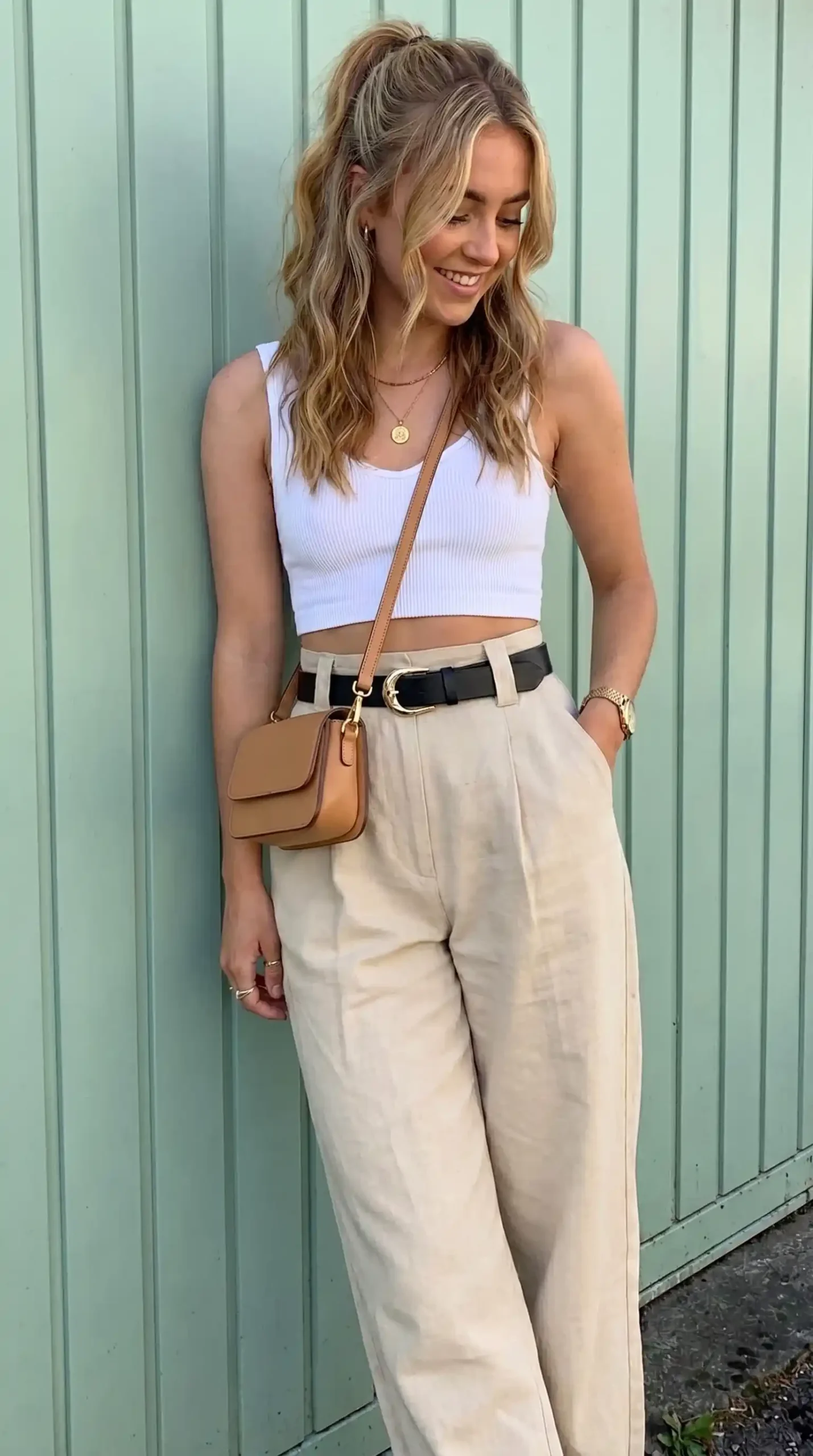 Woman wearing white tank top with beige belted wide-leg trousers outdoors