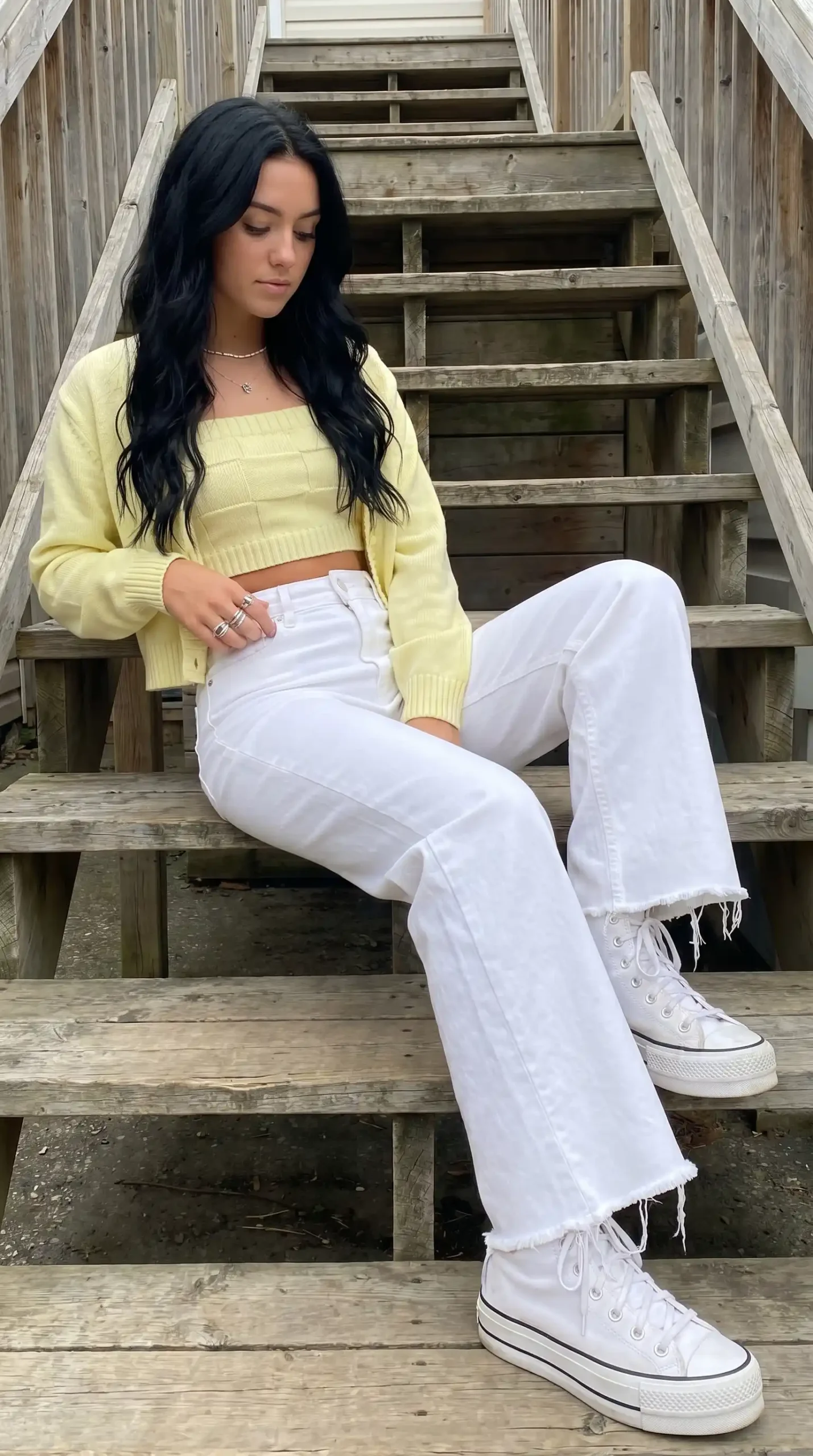 Woman wearing white racerback crop top with beige pleated trousers outdoors