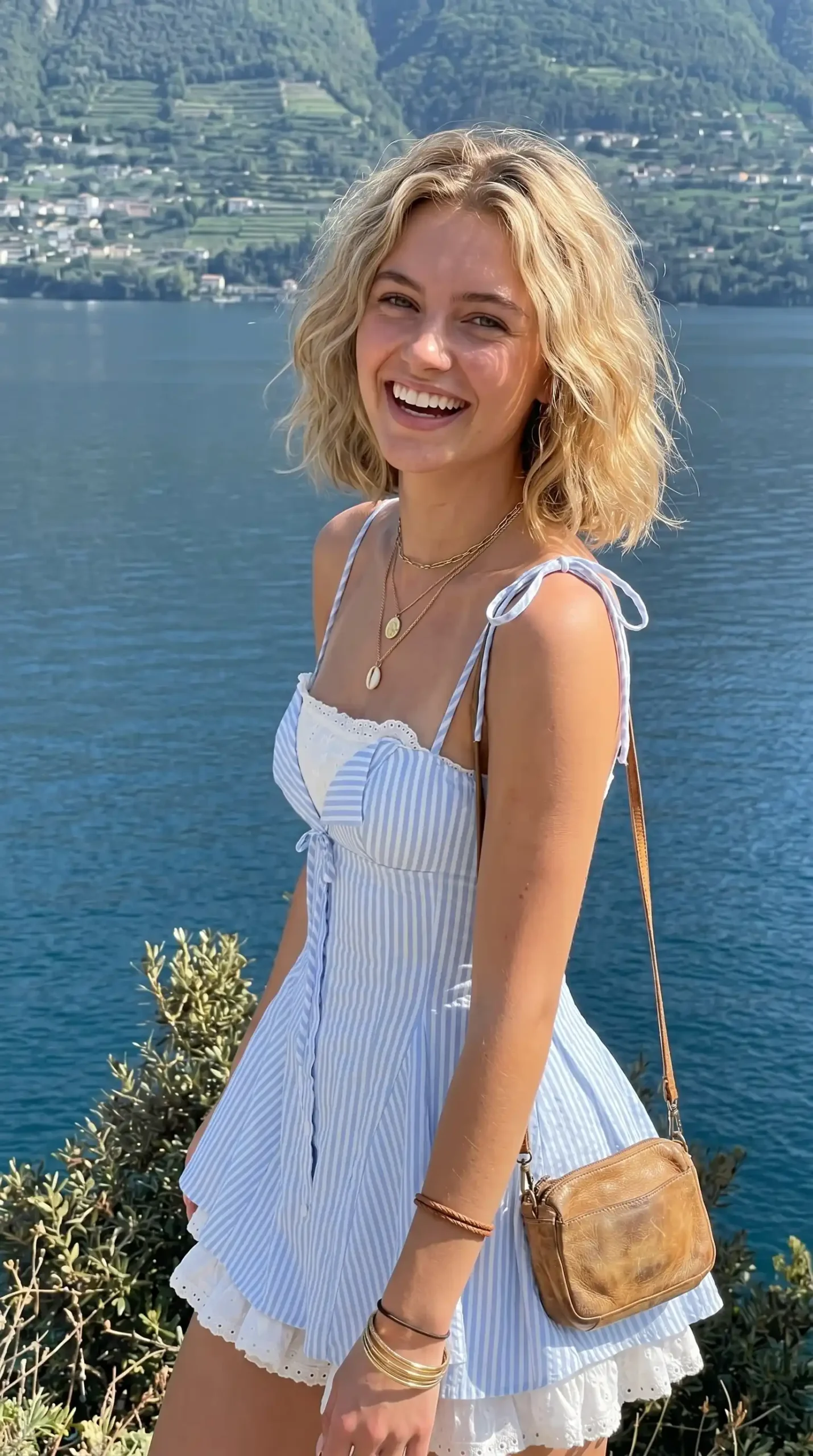 Woman wearing blue and white striped tie-strap mini dress with eyelet trim by the lake