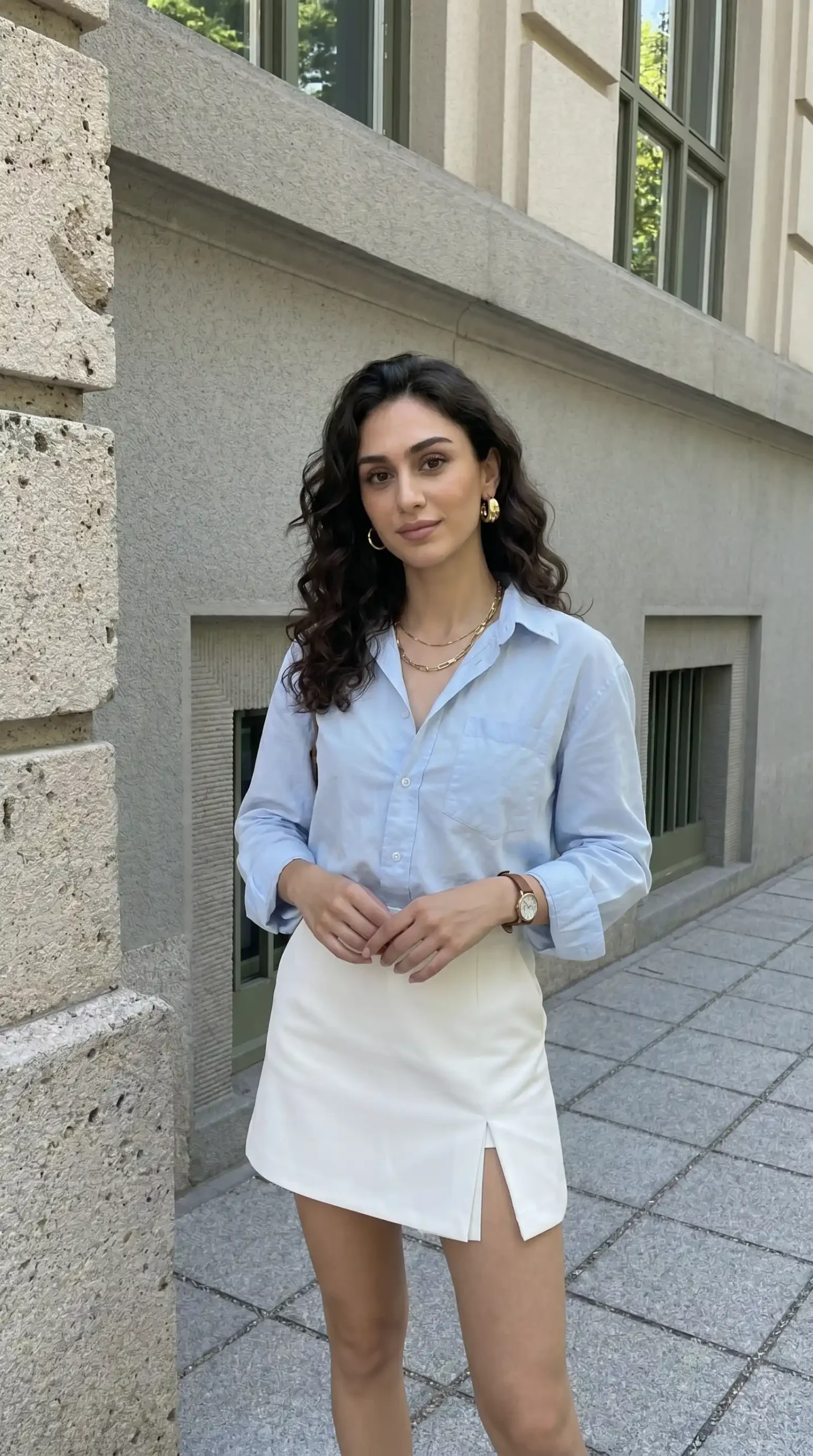 Woman wearing light blue oversized shirt with white mini skirt on city street