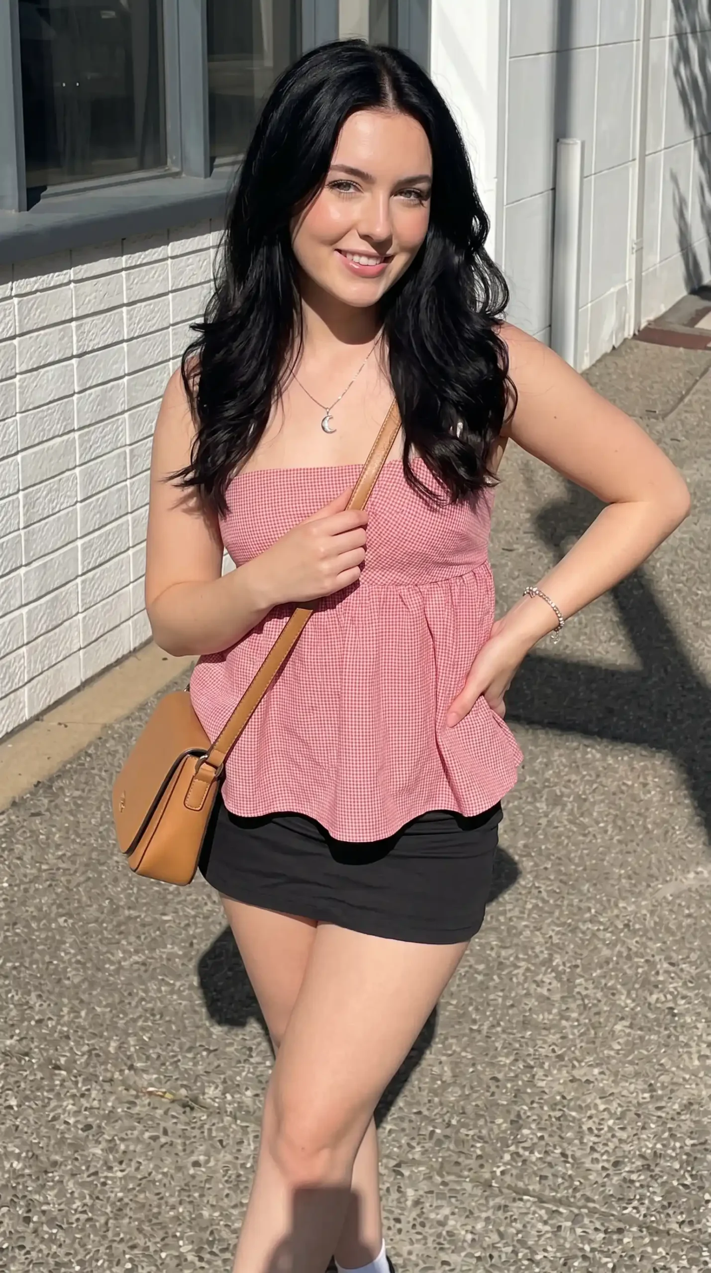 Woman wearing pink gingham peplum tube top with black mini skirt outdoors