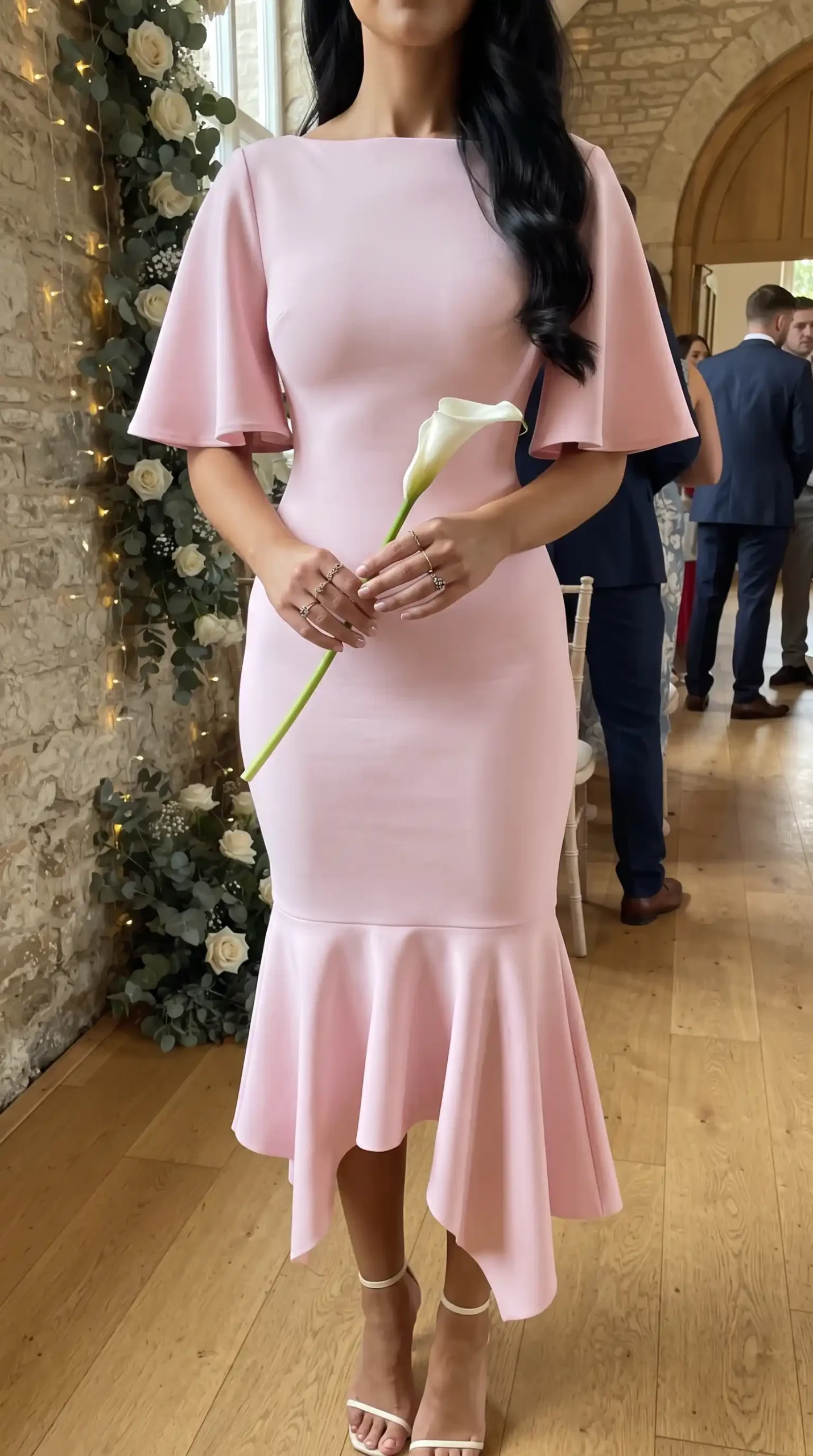 Woman wearing baby pink bateau neck flutter sleeve fitted mermaid ruffle hem midi dress