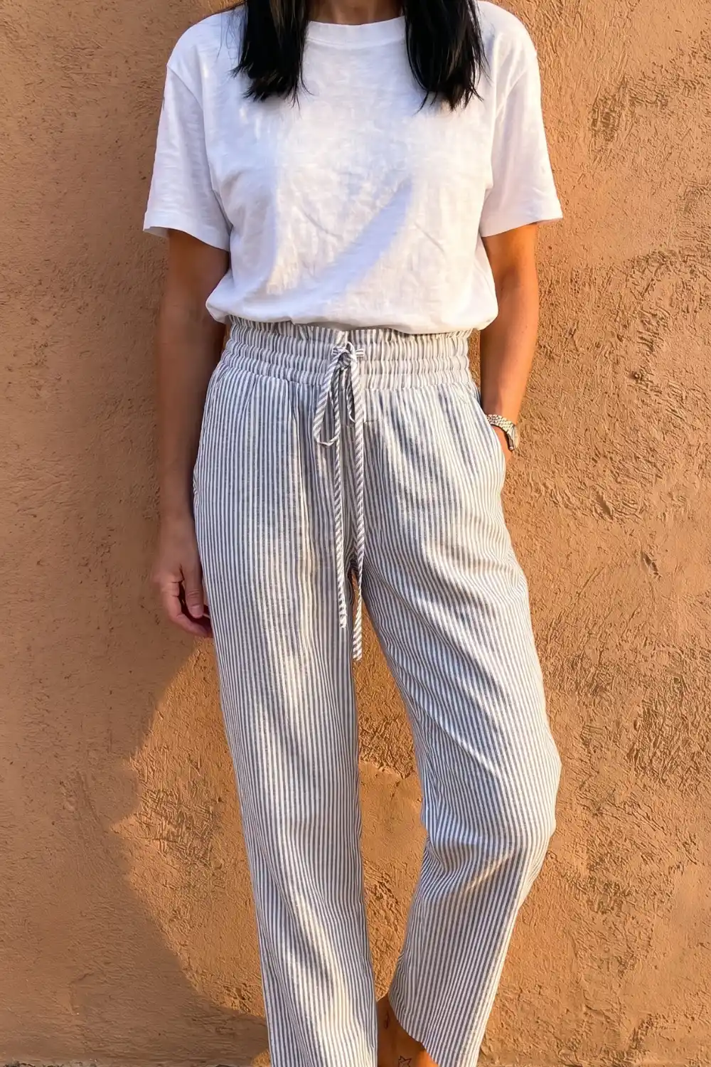 Woman in white crew neck tee with blue white pinstripe linen drawstring tapered pants