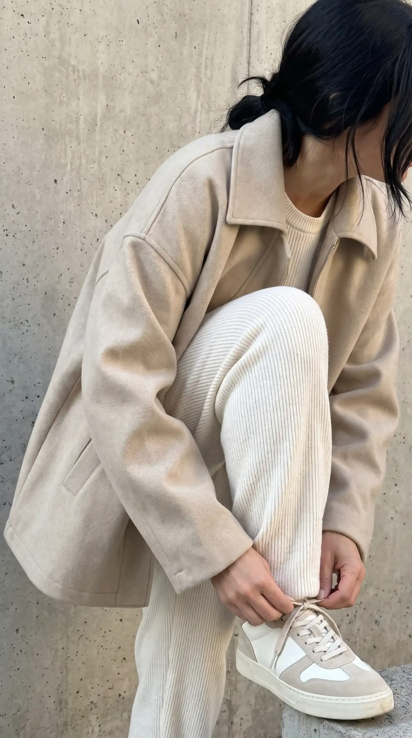 Woman wearing beige wool zip jacket with cream ribbed knit co-ord set and beige sneakers
