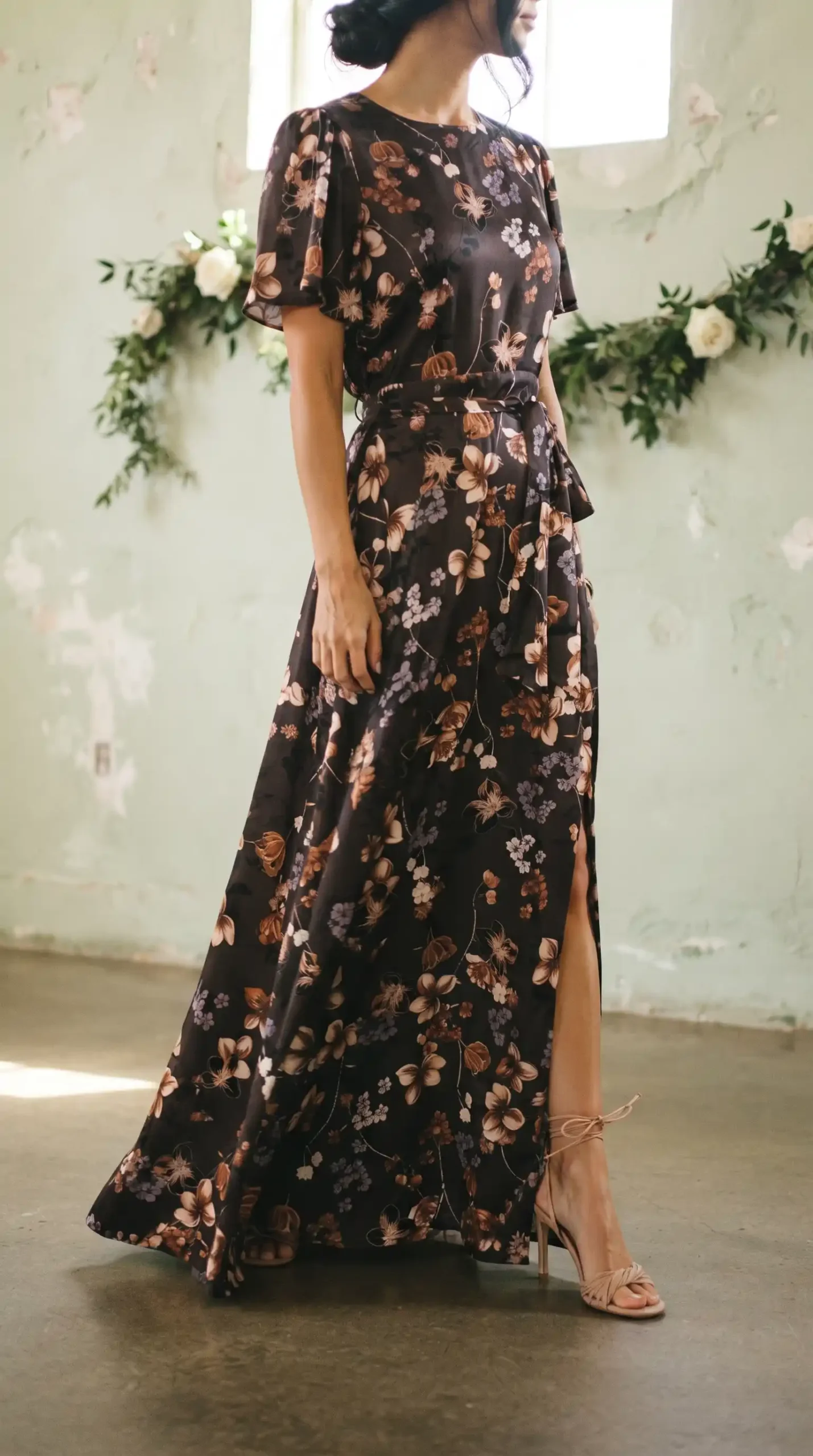 Woman wearing black brown floral satin flutter sleeve belted wrap maxi dress with front slit
