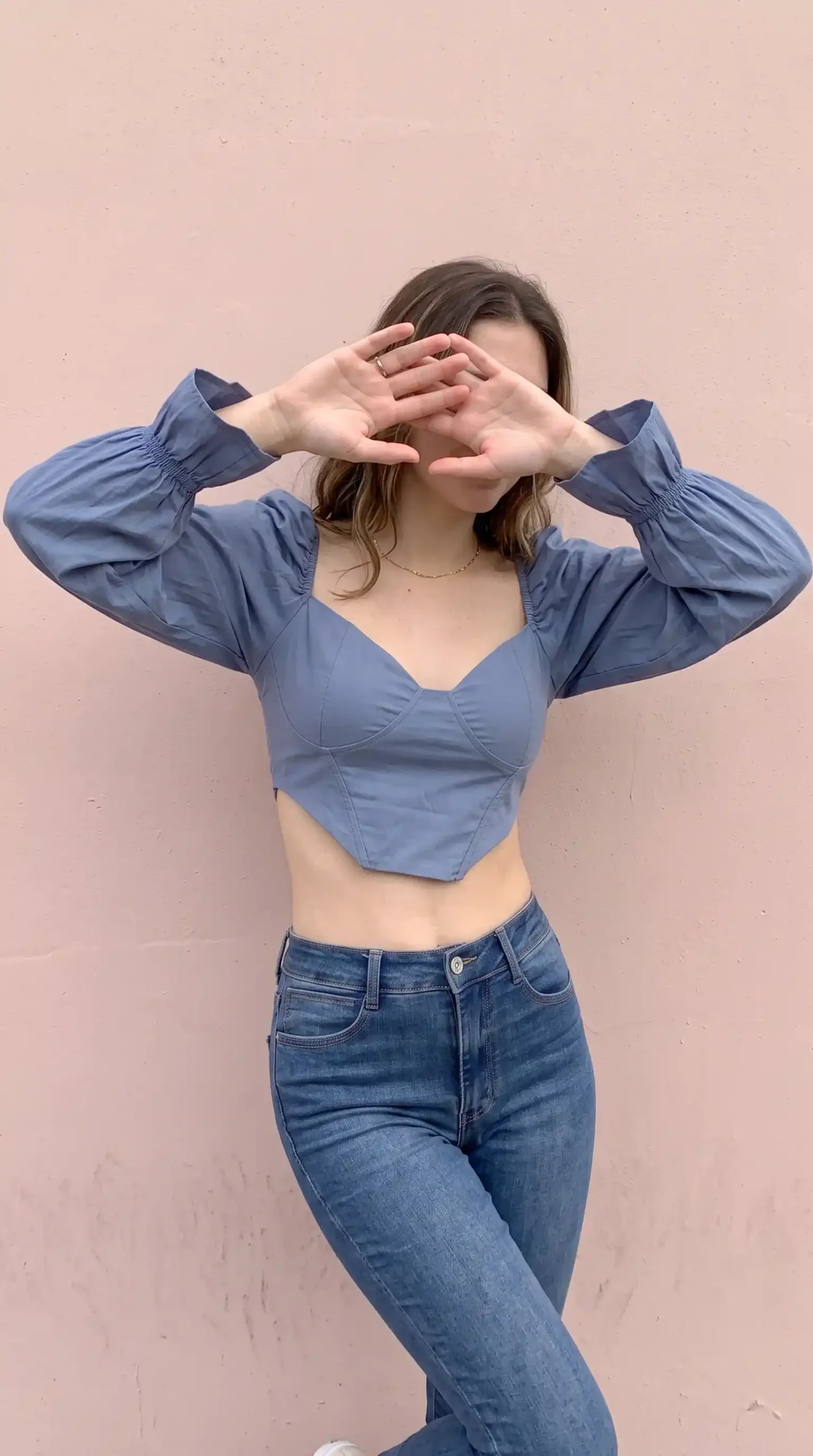 Woman wearing slate blue sweetheart corset puff sleeve crop blouse with mid wash skinny jeans