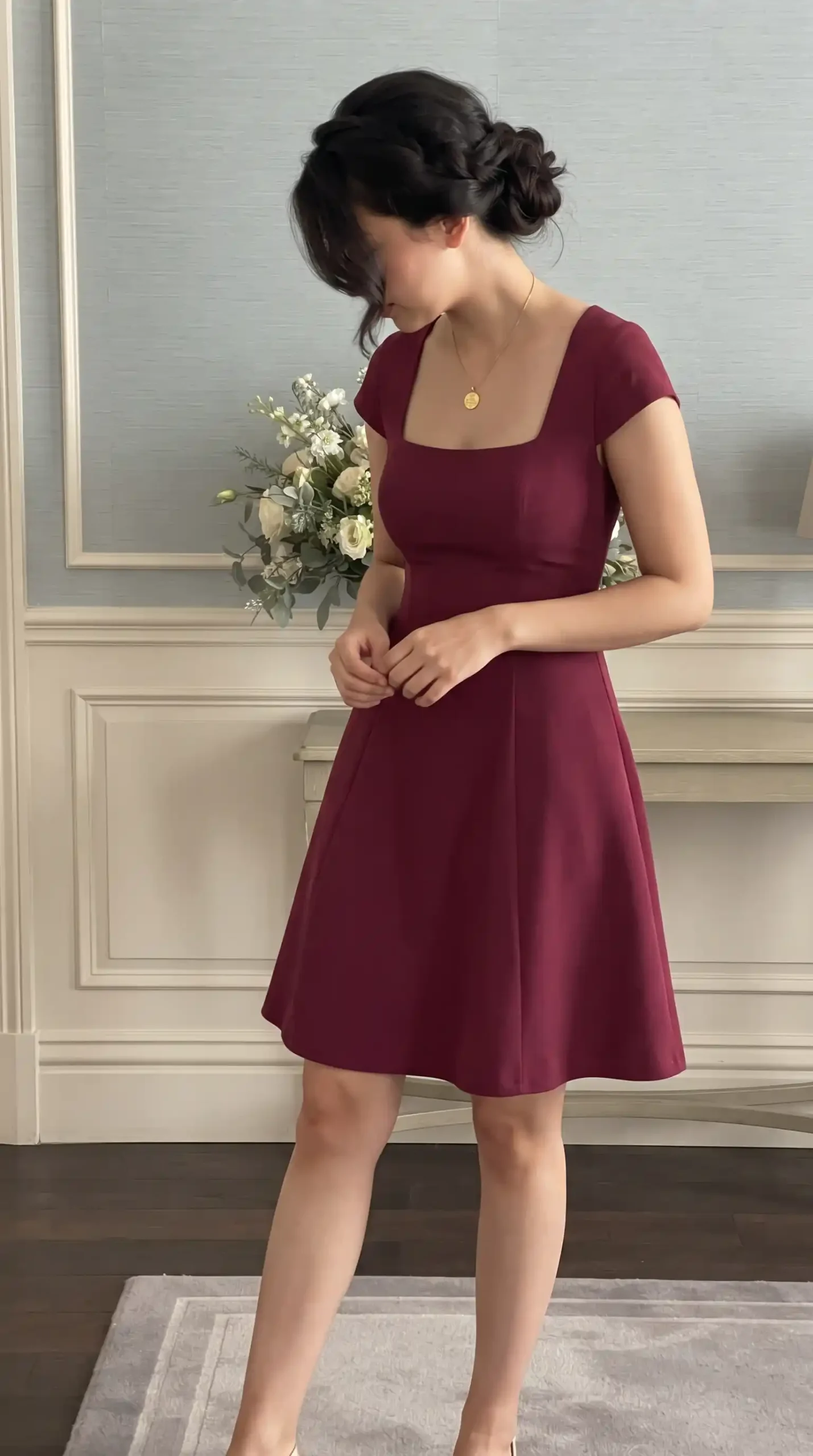 Woman wearing burgundy square neck cap sleeve A-line mini dress holding white floral bouquet