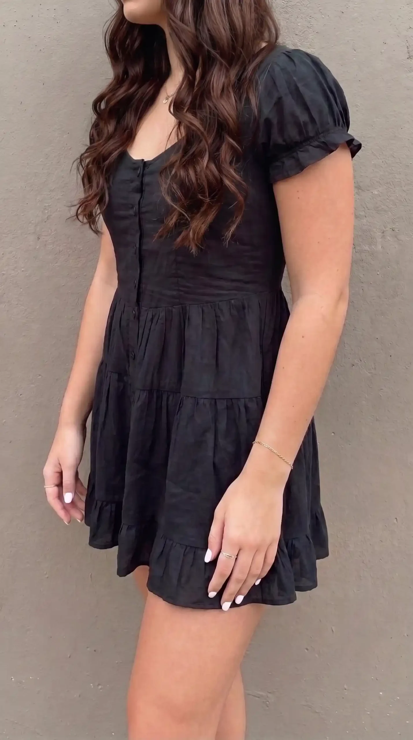 Woman in black puff sleeve button front tiered mini dress