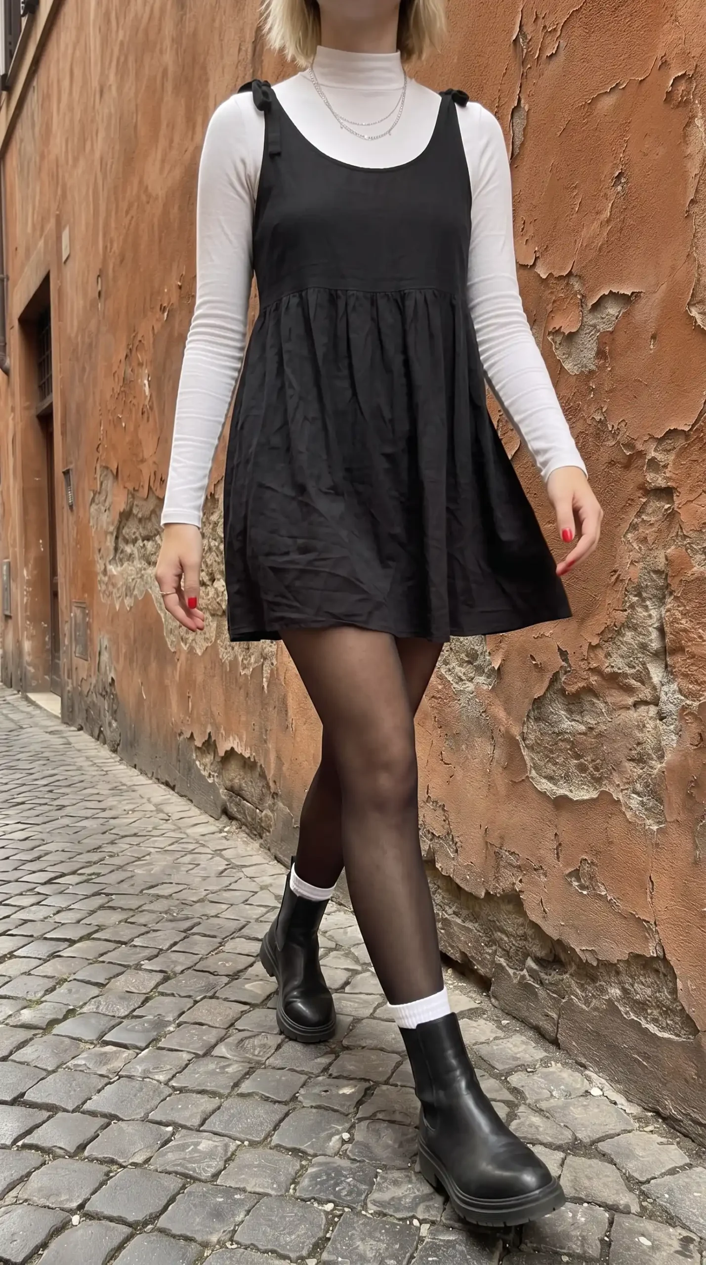 Woman in white turtleneck under black babydoll mini dress with sheer tights white socks