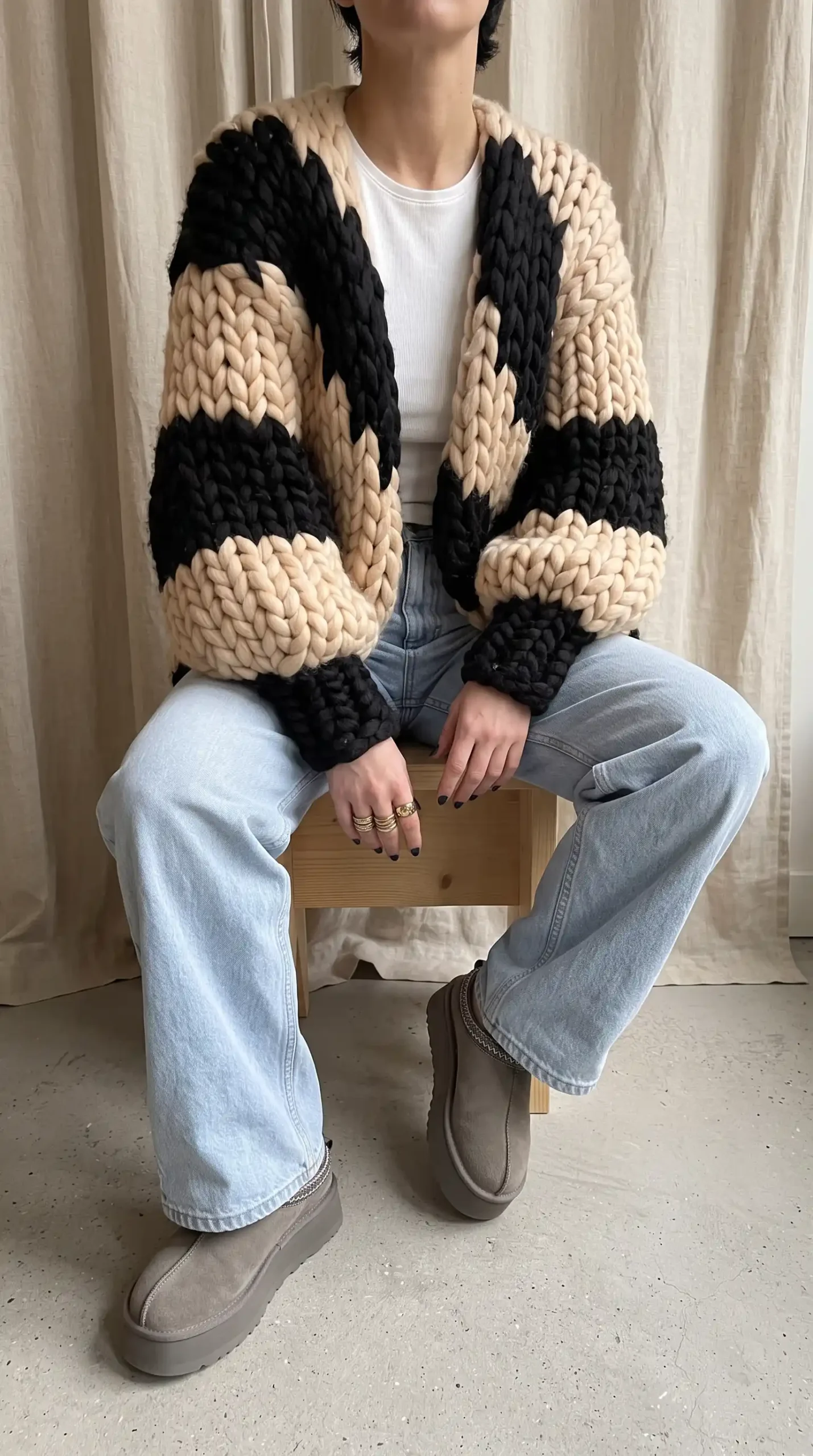 Woman in cream black chevron chunky knit cardigan with white crop tank light wash wide leg jeans