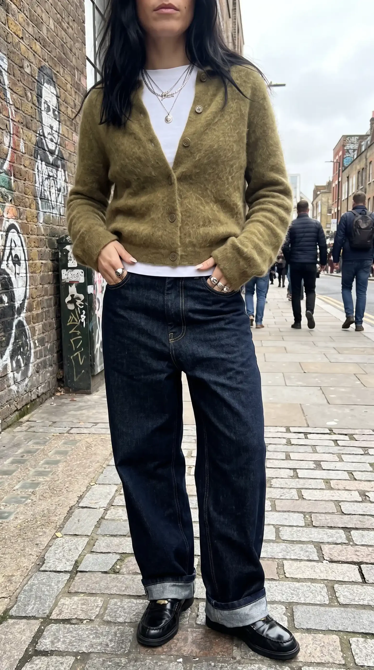 Woman wearing olive green fluffy cardigan with white tee dark wash wide leg jeans and black loafers on London street