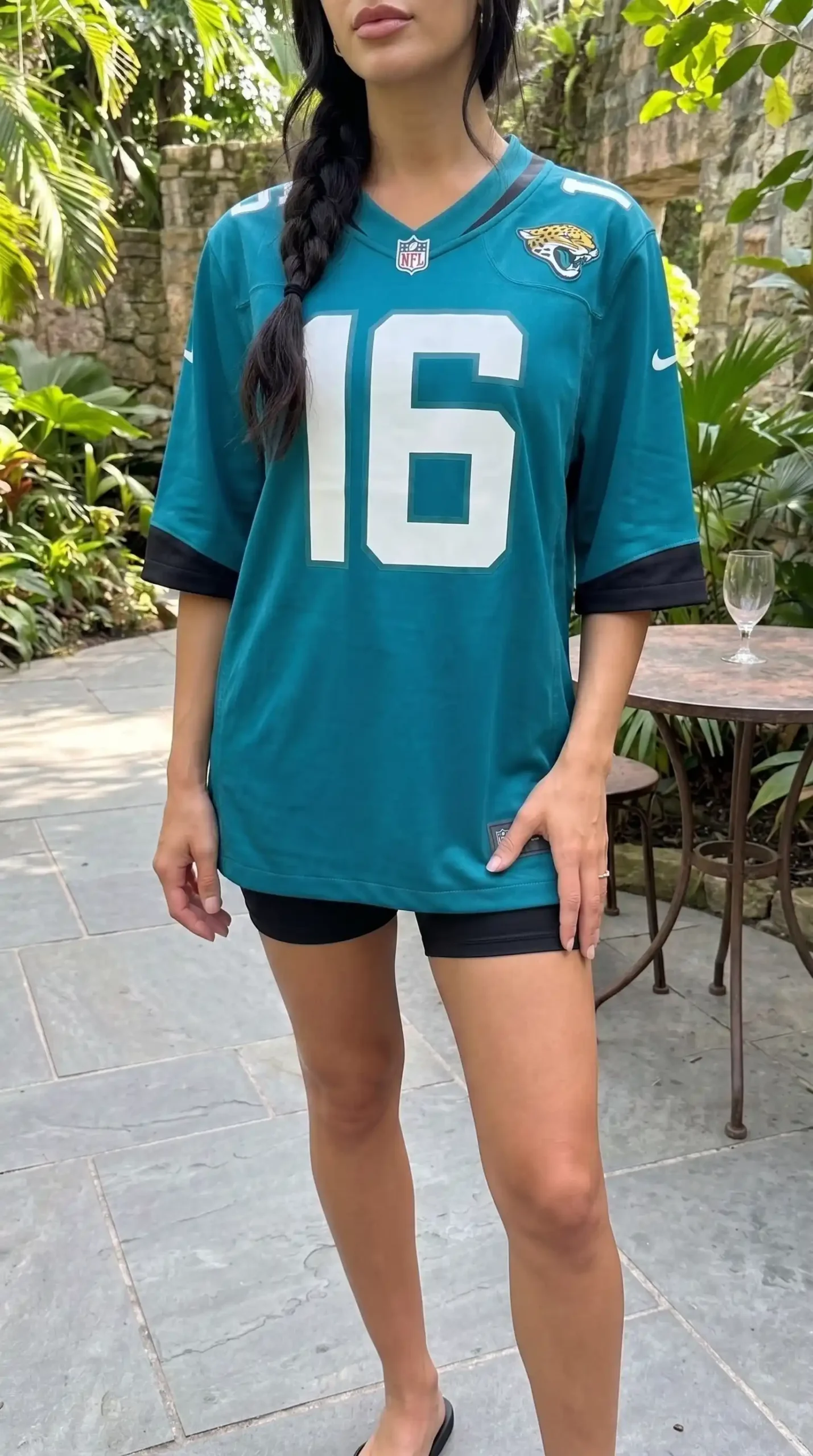 Woman wearing teal Jacksonville Jaguars oversized number 16 jersey with black biker shorts outdoors
