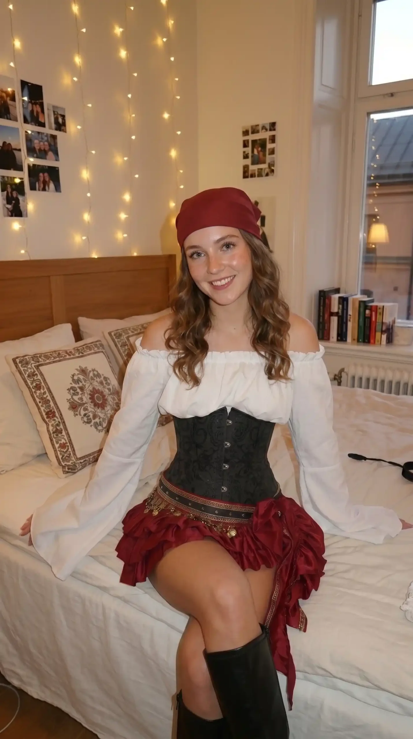 Woman dressed as female pirate in white off-shoulder blouse black brocade corset burgundy ruffle skirt and red bandana