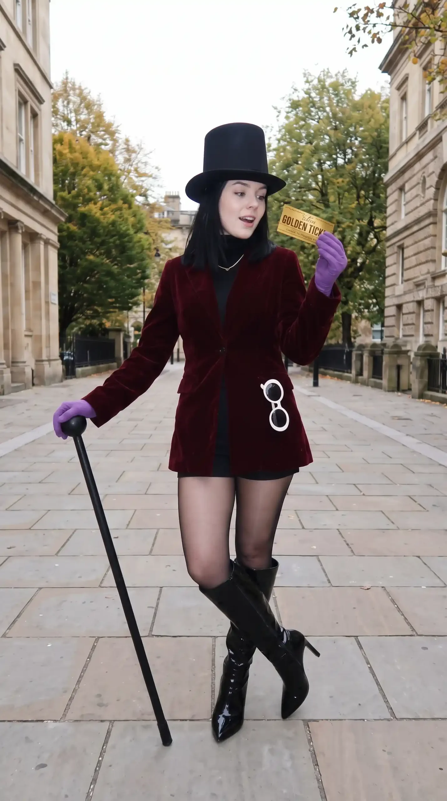 Woman dressed as Willy Wonka in burgundy velvet blazer black mini dress top hat and patent knee high boots
