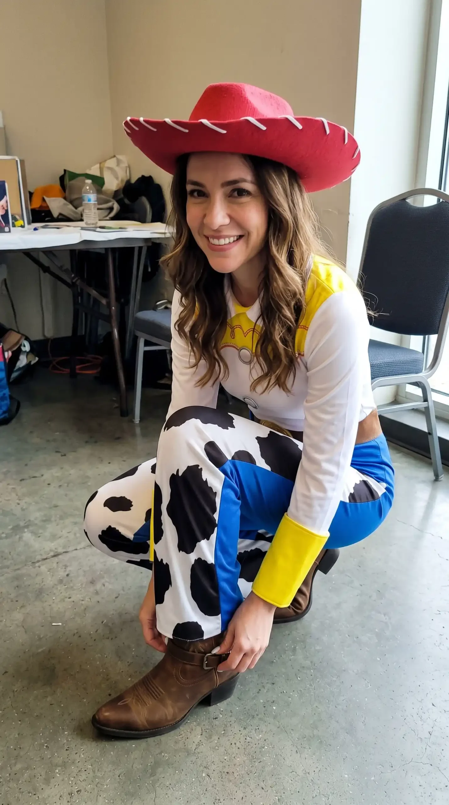 Woman dressed as Jessie from Toy Story in white cowgirl top with blue pants cow print chaps