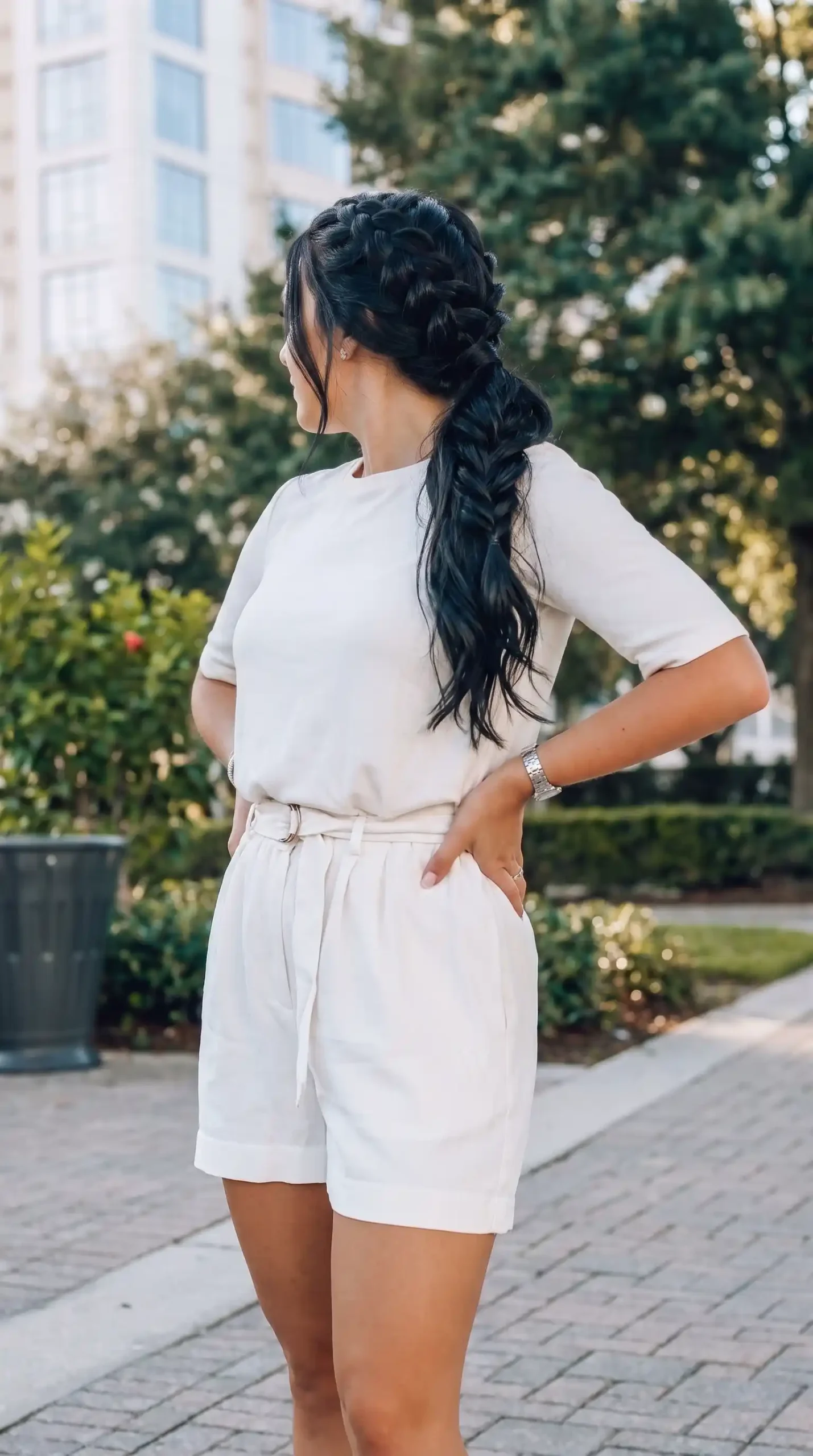 Woman wearing cream short sleeve knit top with cream belted paperbag waist linen shorts outdoors