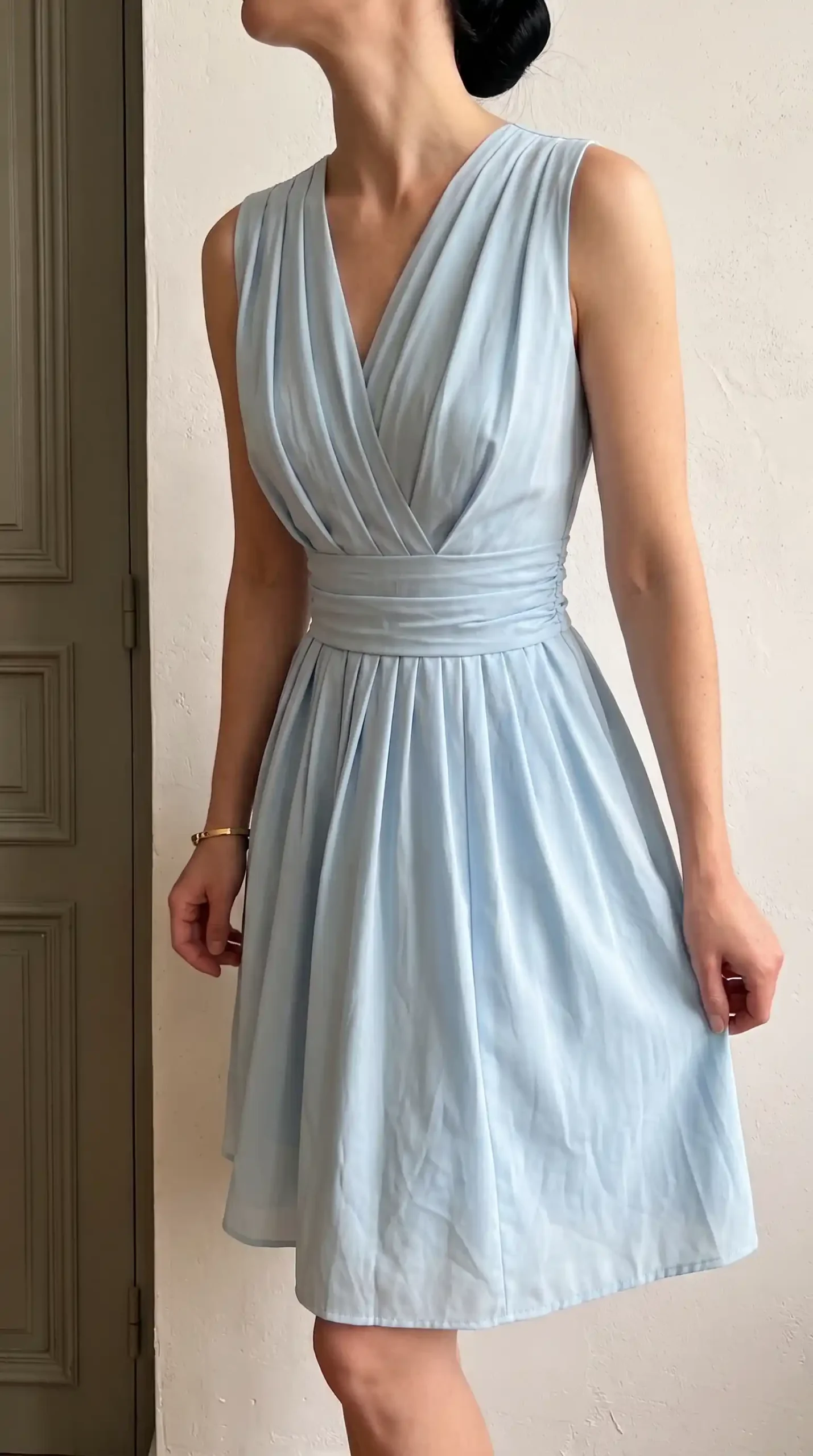 Pale blue sleeveless V neck pleated waist fit and flare dress indoors