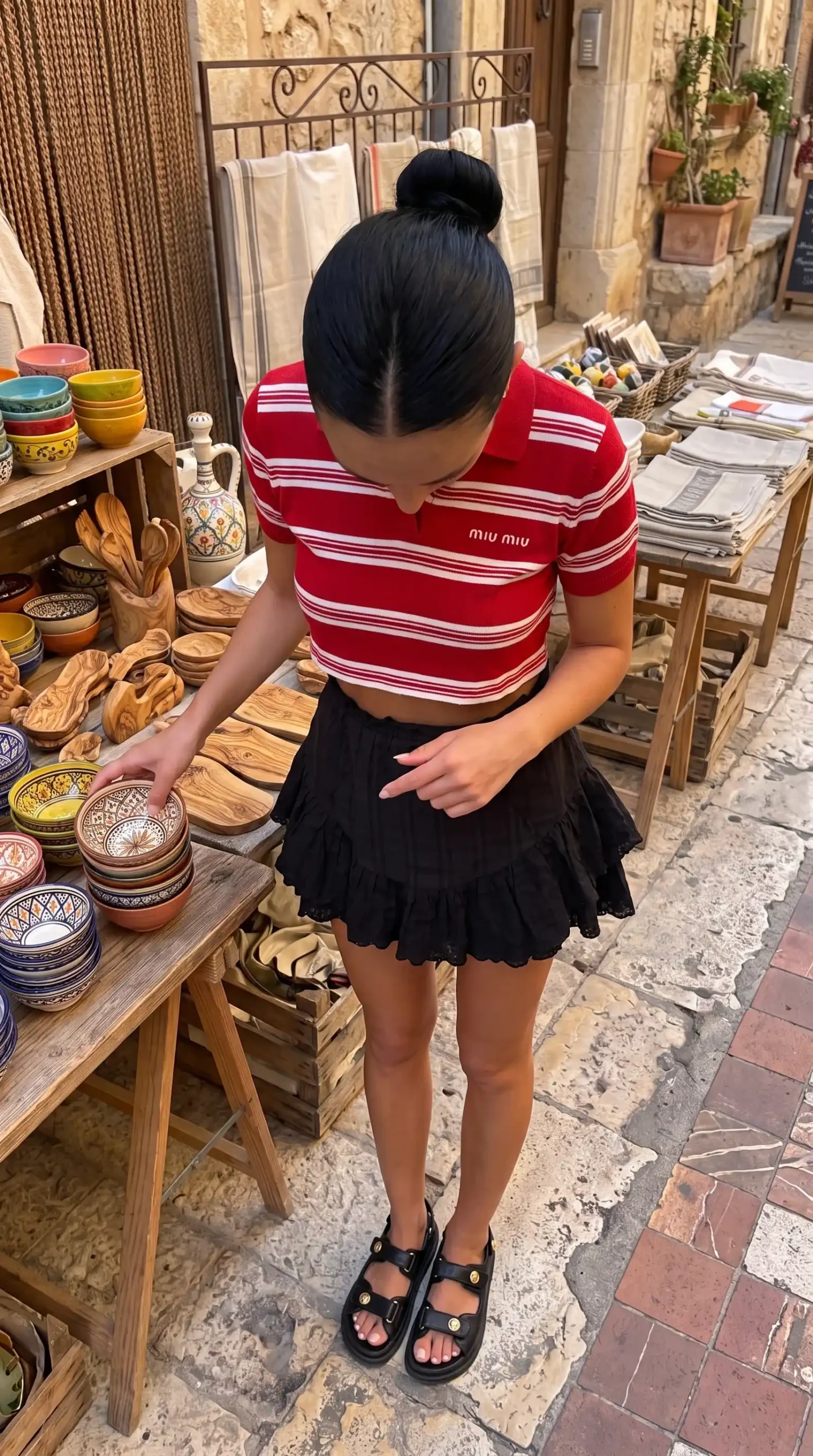 Woman wearing red striped crop polo top and black eyelet ruffle mini skirt at European market