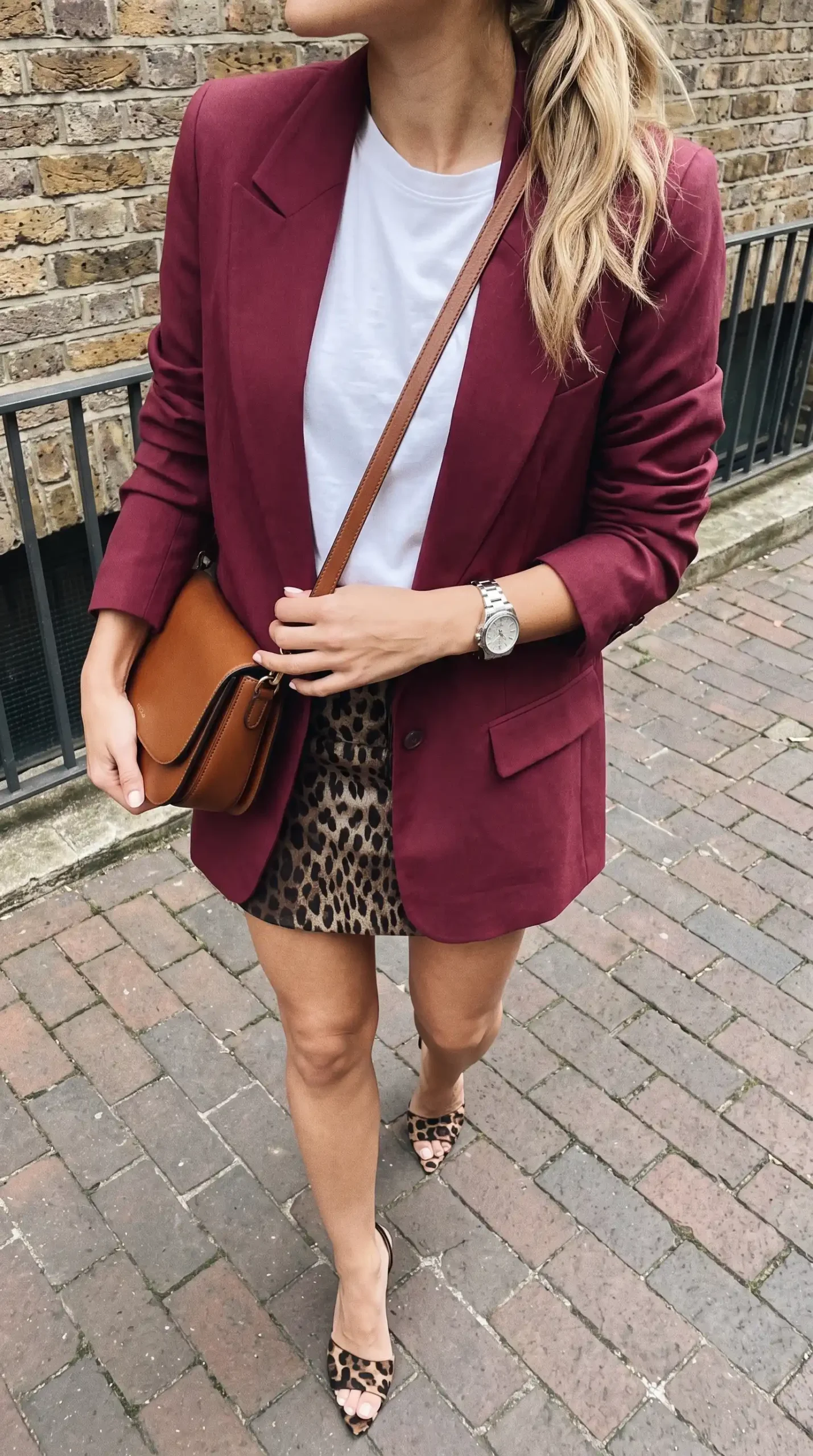 Woman wearing burgundy oversized blazer with white tee leopard print mini skirt and leopard heels outdoors