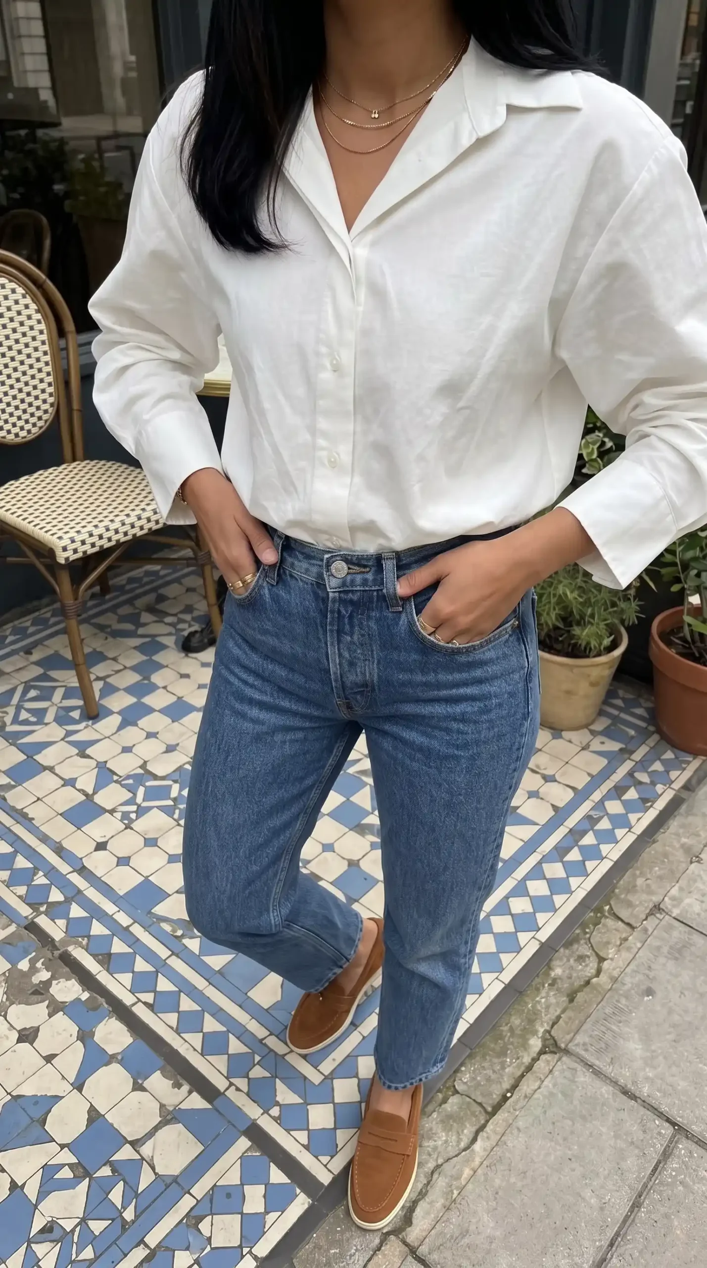 Woman wearing white linen oversized shirt with mid wash straight jeans and tan loafers outdoors