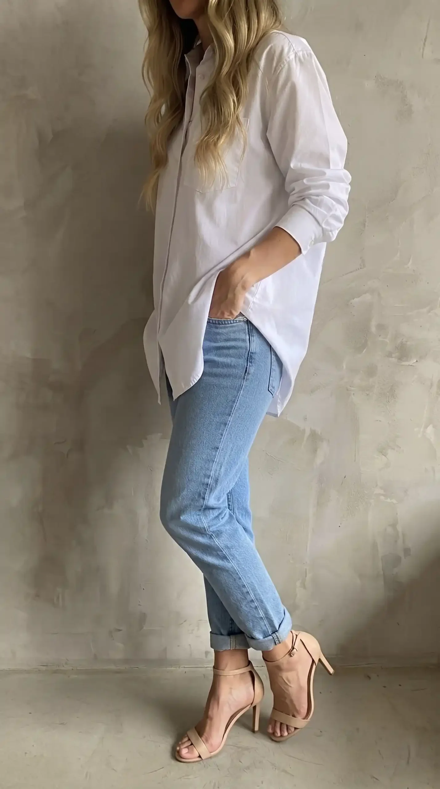 Woman wearing white oversized shirt with light wash rolled hem mom jeans and nude heels