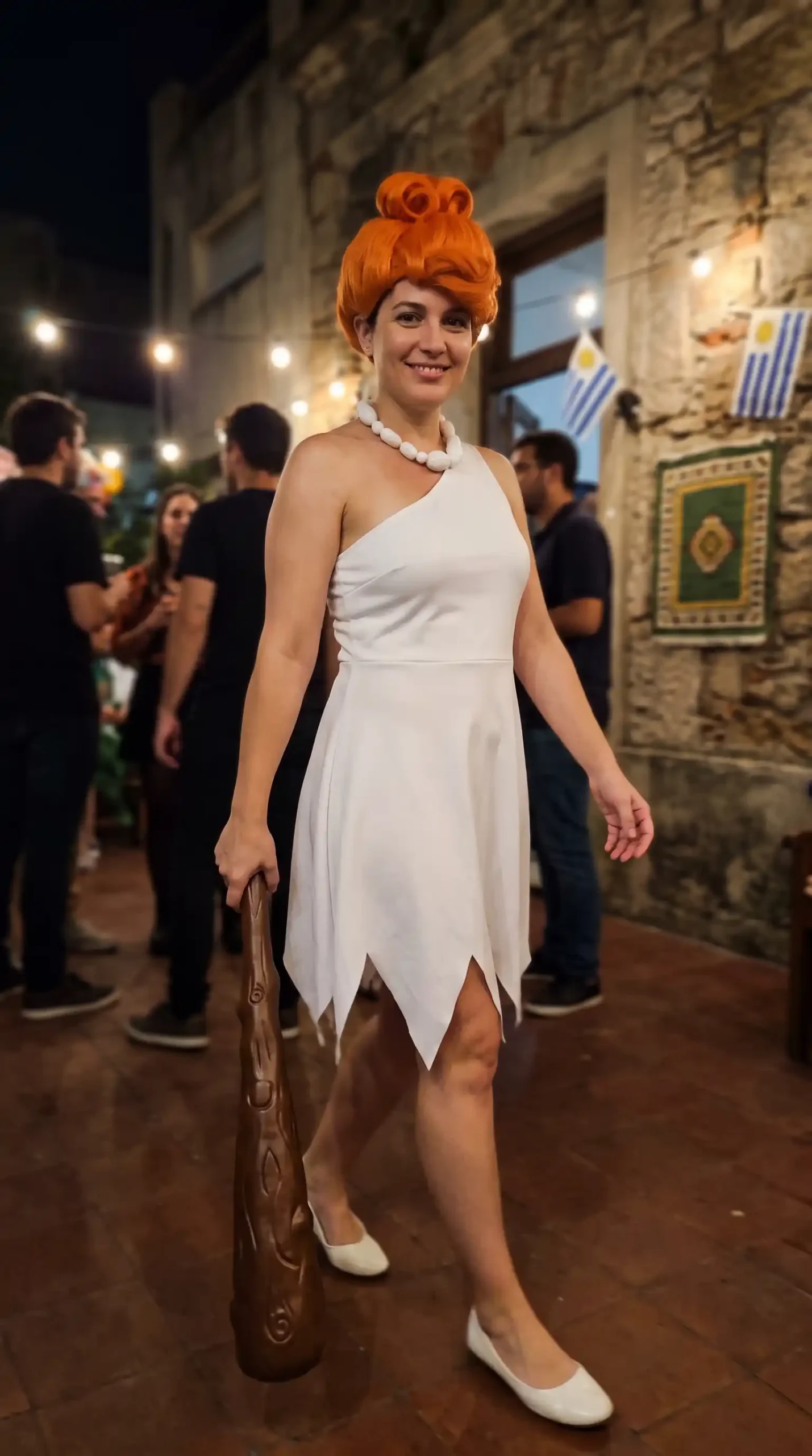 dressed as Wilma Flintstone in white one shoulder jagged hem mini dress