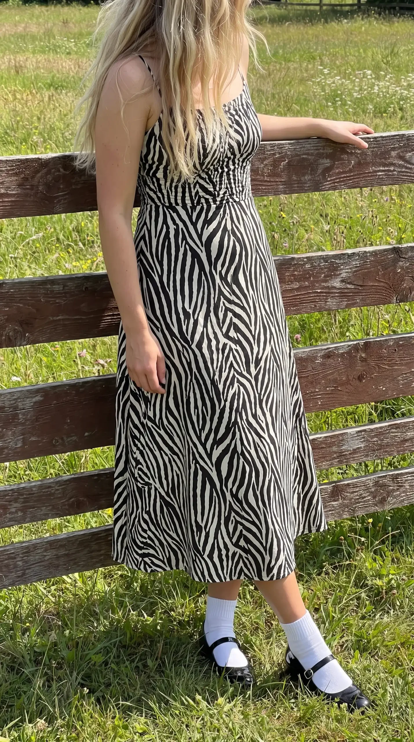 Woman wearing black white zebra print smocked midi dress with white socks and black Mary Jane heels outdoors