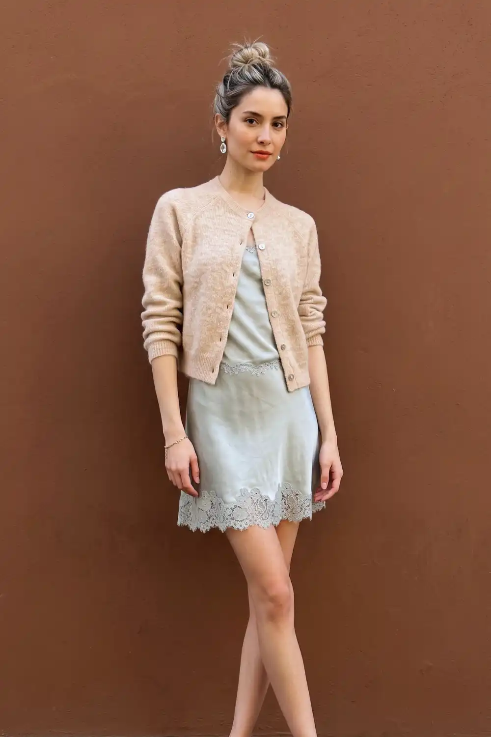 Woman in beige fuzzy cropped cardigan over sage green satin lace trim mini slip dress
