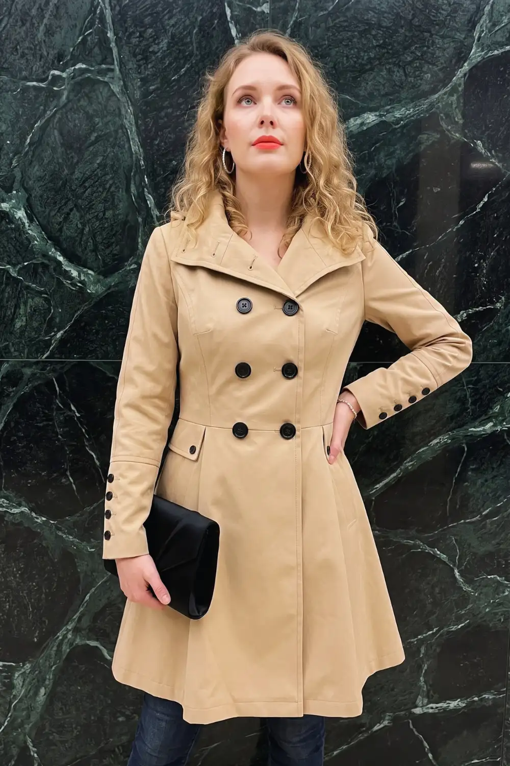 Woman in sand beige fit and flare double-breasted trench coat with dark wash jeans