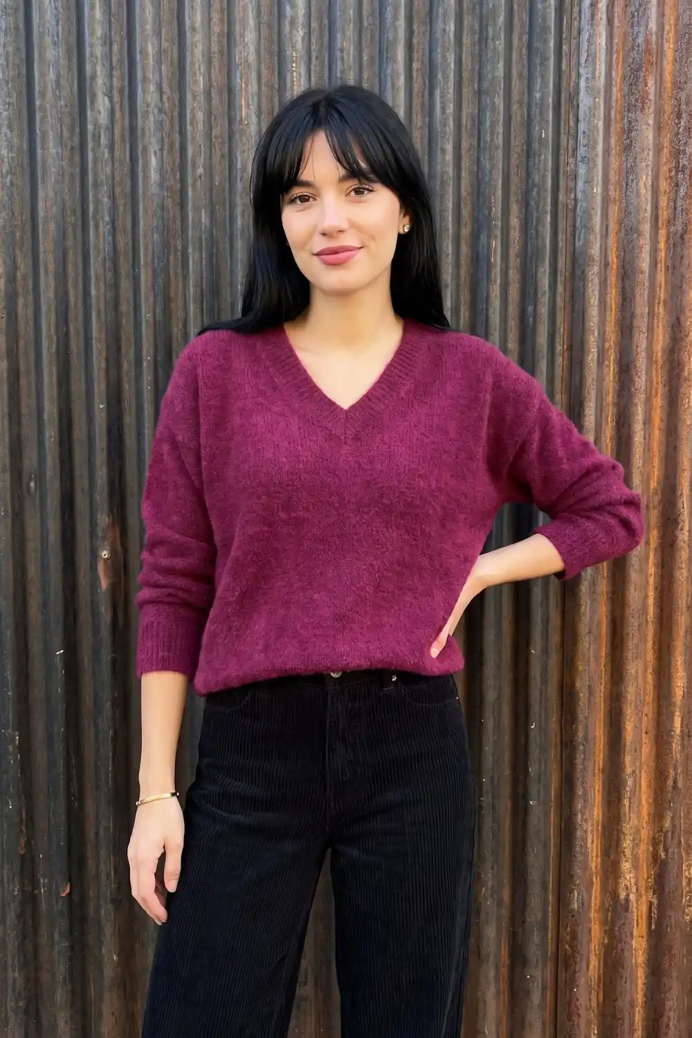 Woman wearing berry magenta fluffy v-neck knit sweater with black corduroy wide leg trousers