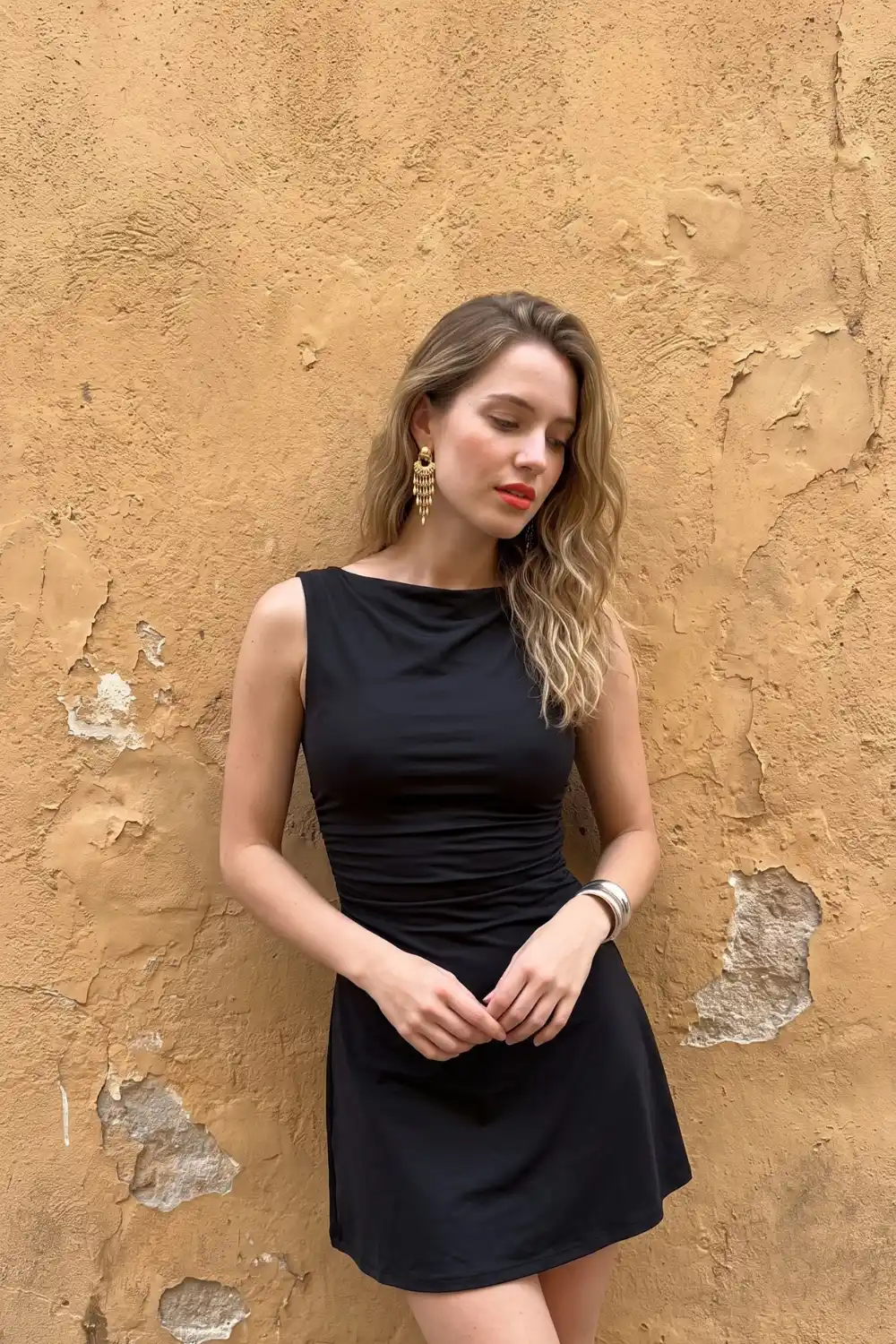 Woman wearing black sleeveless bateau neck ruched waist mini dress