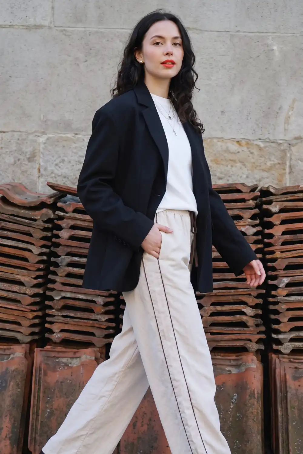 Woman in black oversized blazer with white tee and cream side stripe wide leg trousers