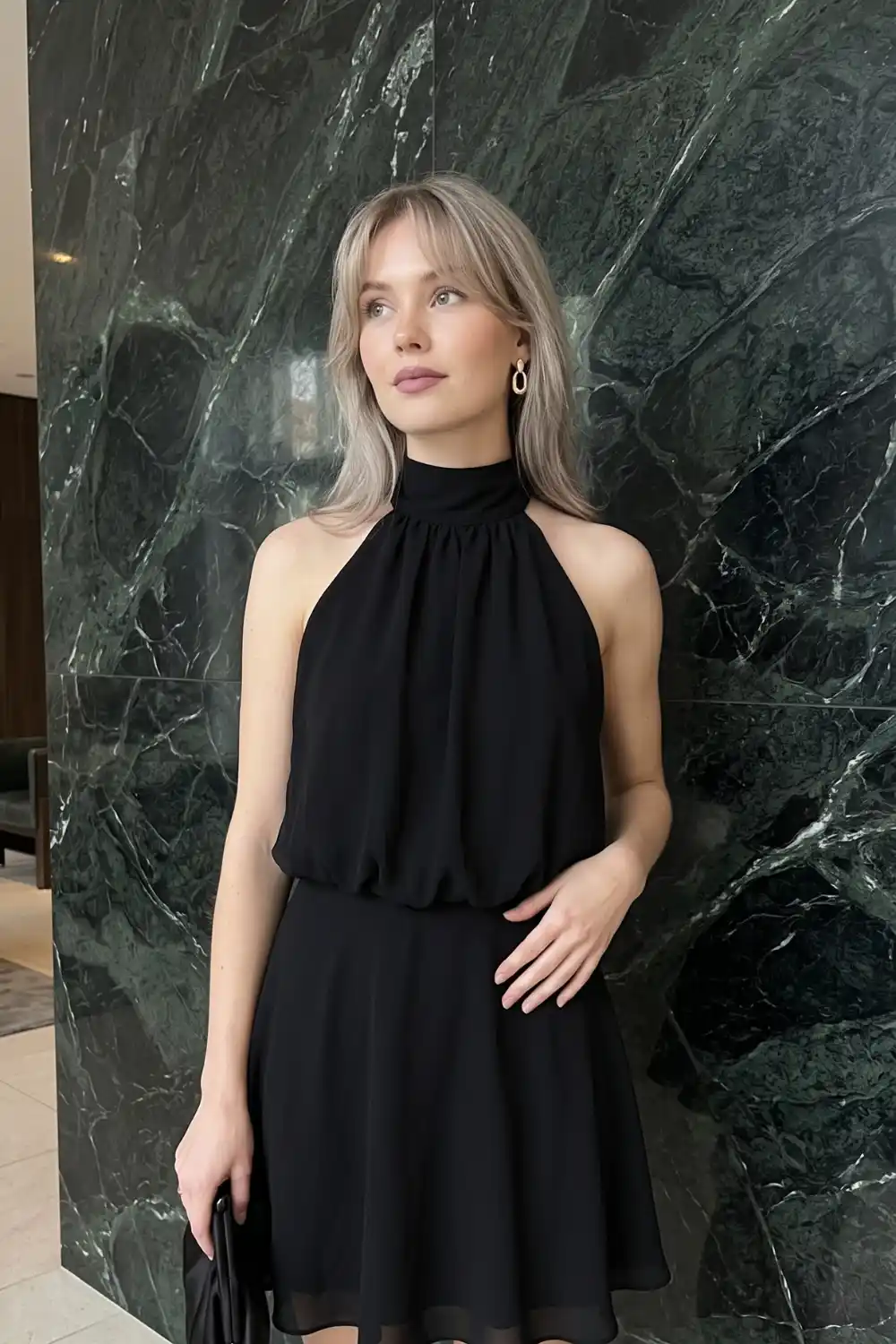 Woman wearing black chiffon halter neck gathered blouson mini dress